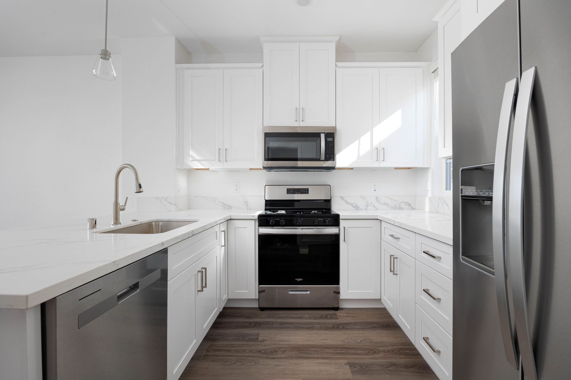 a kitchen with white cabinets , stainless steel appliances , a sink , and a refrigerator .