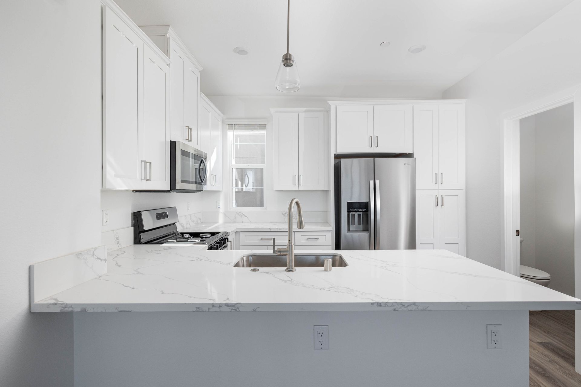 a kitchen with white cabinets , stainless steel appliances , a sink , and a refrigerator .