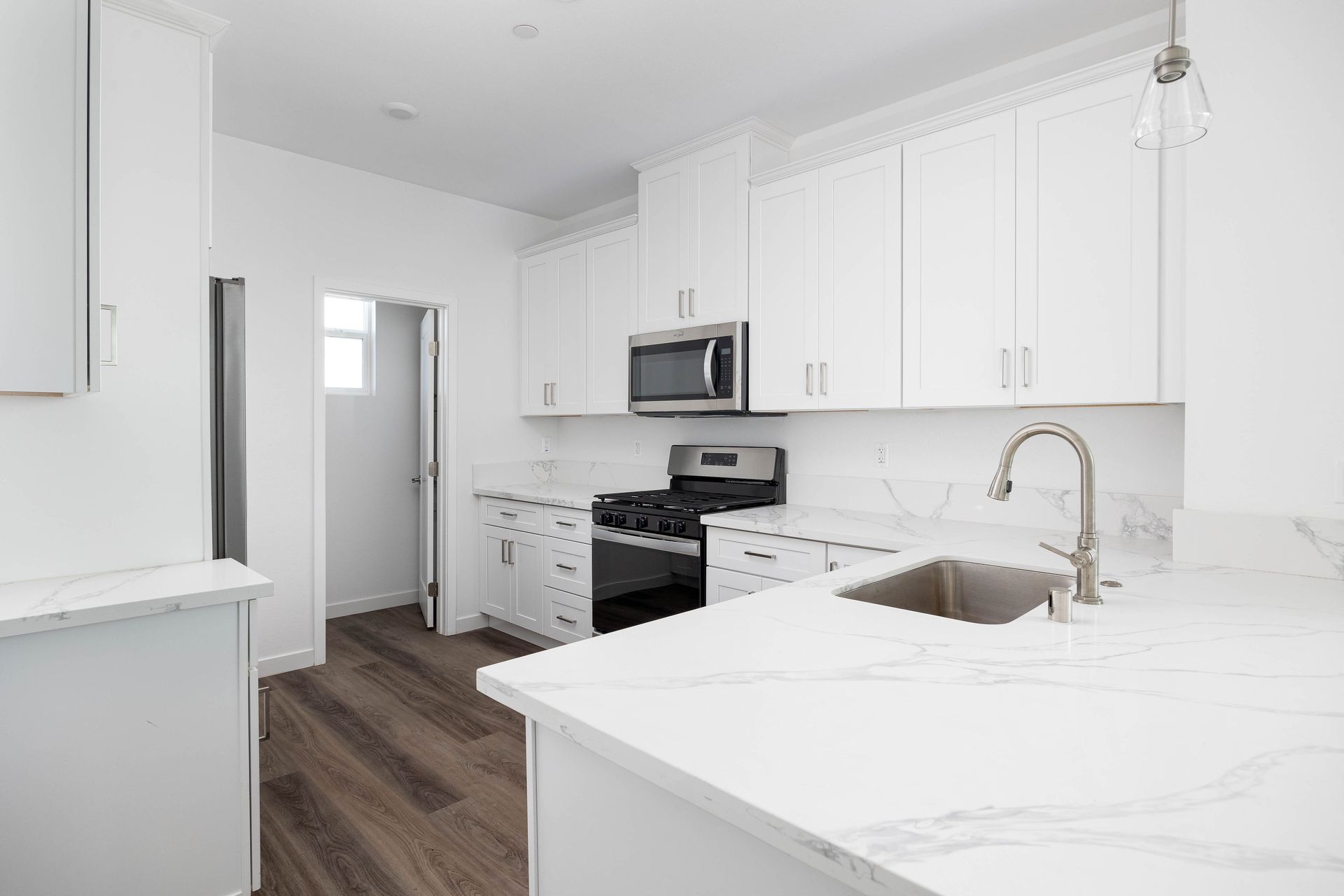 a kitchen with white cabinets , stainless steel appliances , a sink , and a microwave .