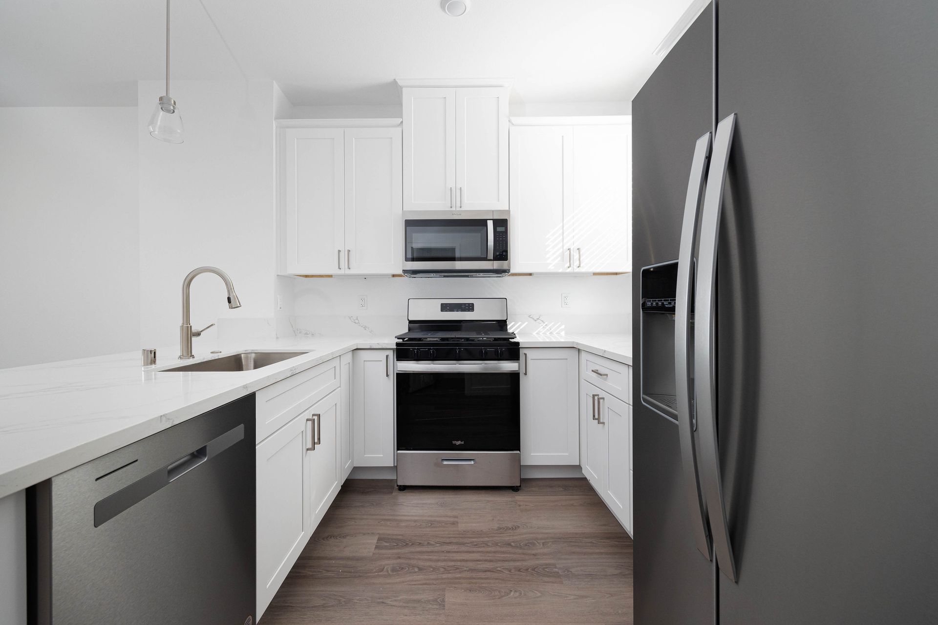 a kitchen with white cabinets , stainless steel appliances and a black refrigerator .