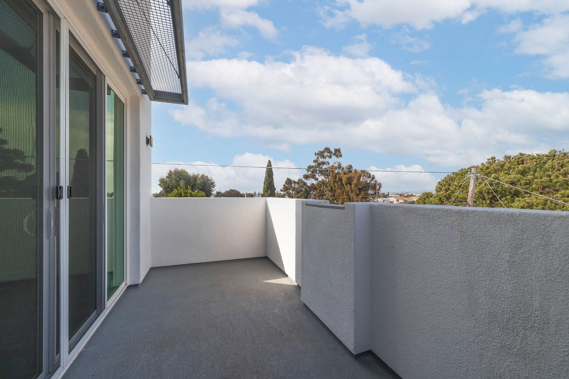a balcony with a view of trees and a blue sky
