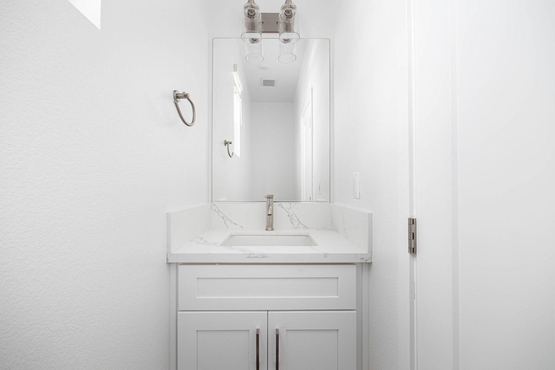 a bathroom with a sink , mirror and cabinets .