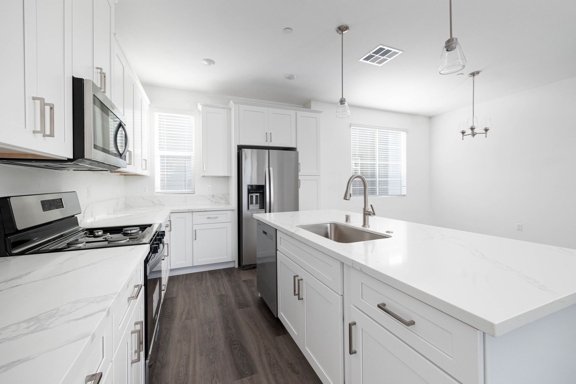 a kitchen with white cabinets , stainless steel appliances , and a large island .