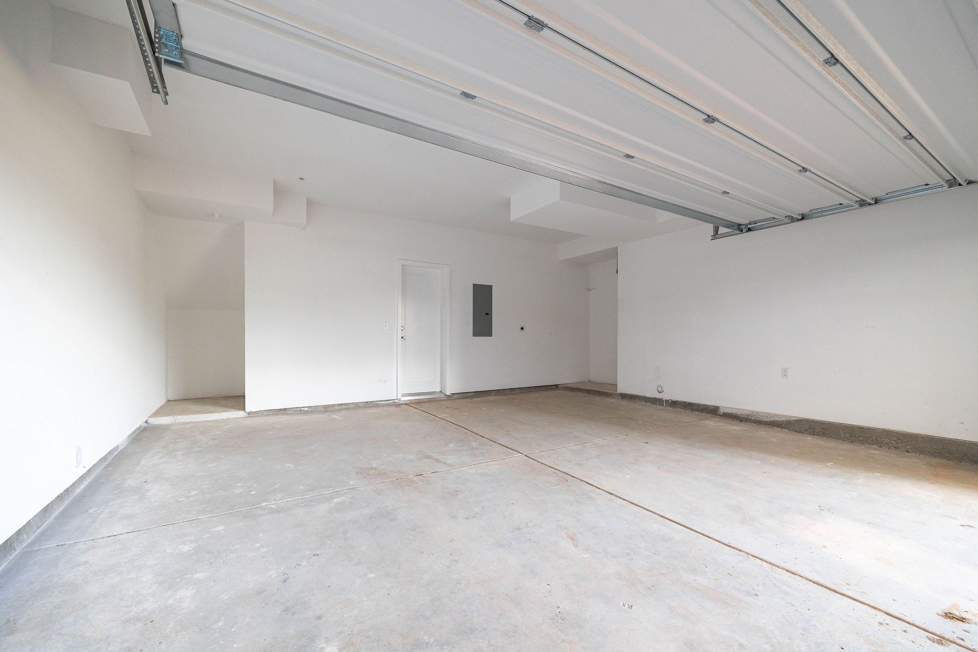 an empty garage with a garage door open and a concrete floor .