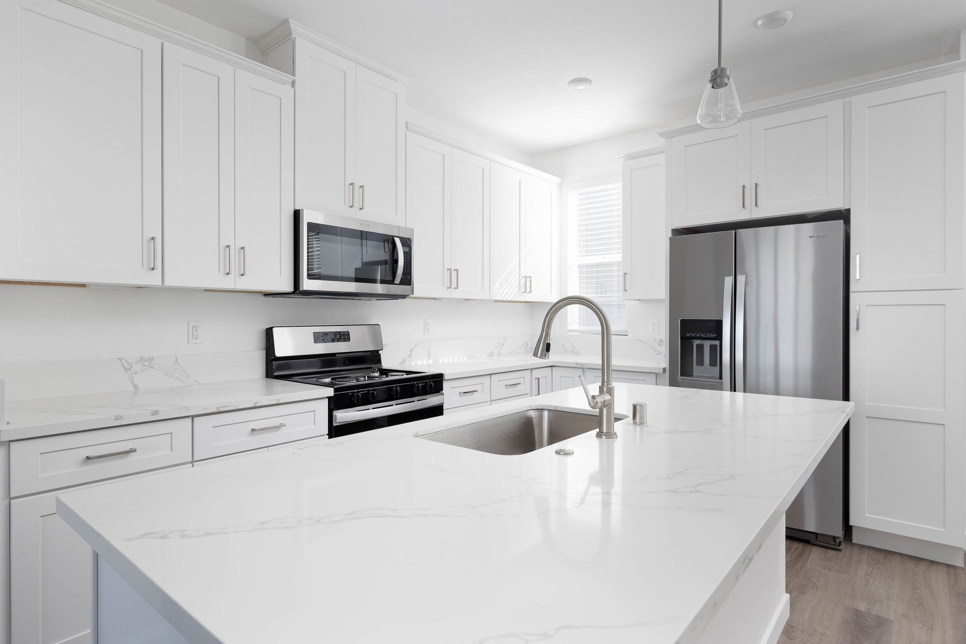 a kitchen with white cabinets , stainless steel appliances , a sink and a refrigerator .