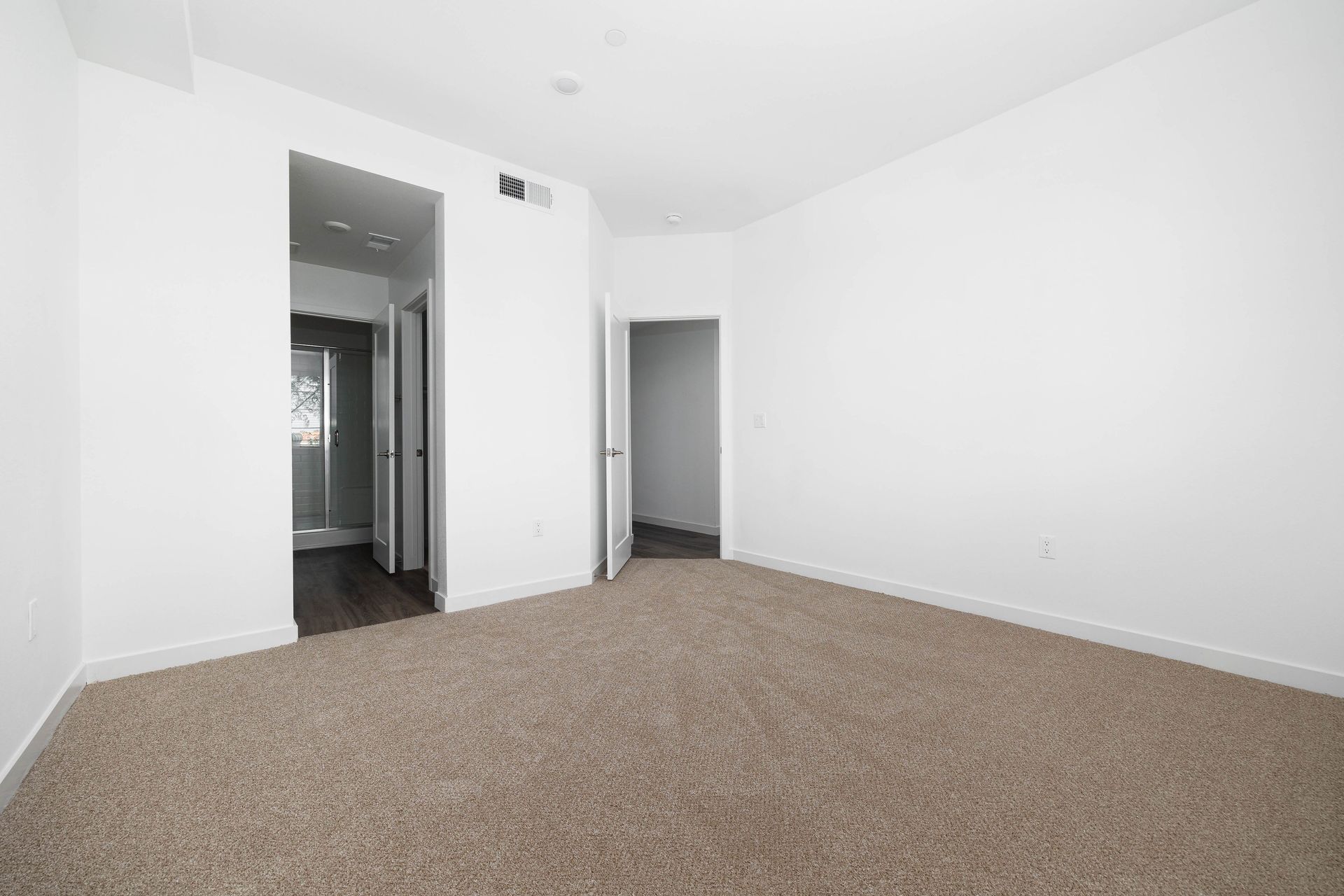an empty bedroom with a brown carpet and white walls .