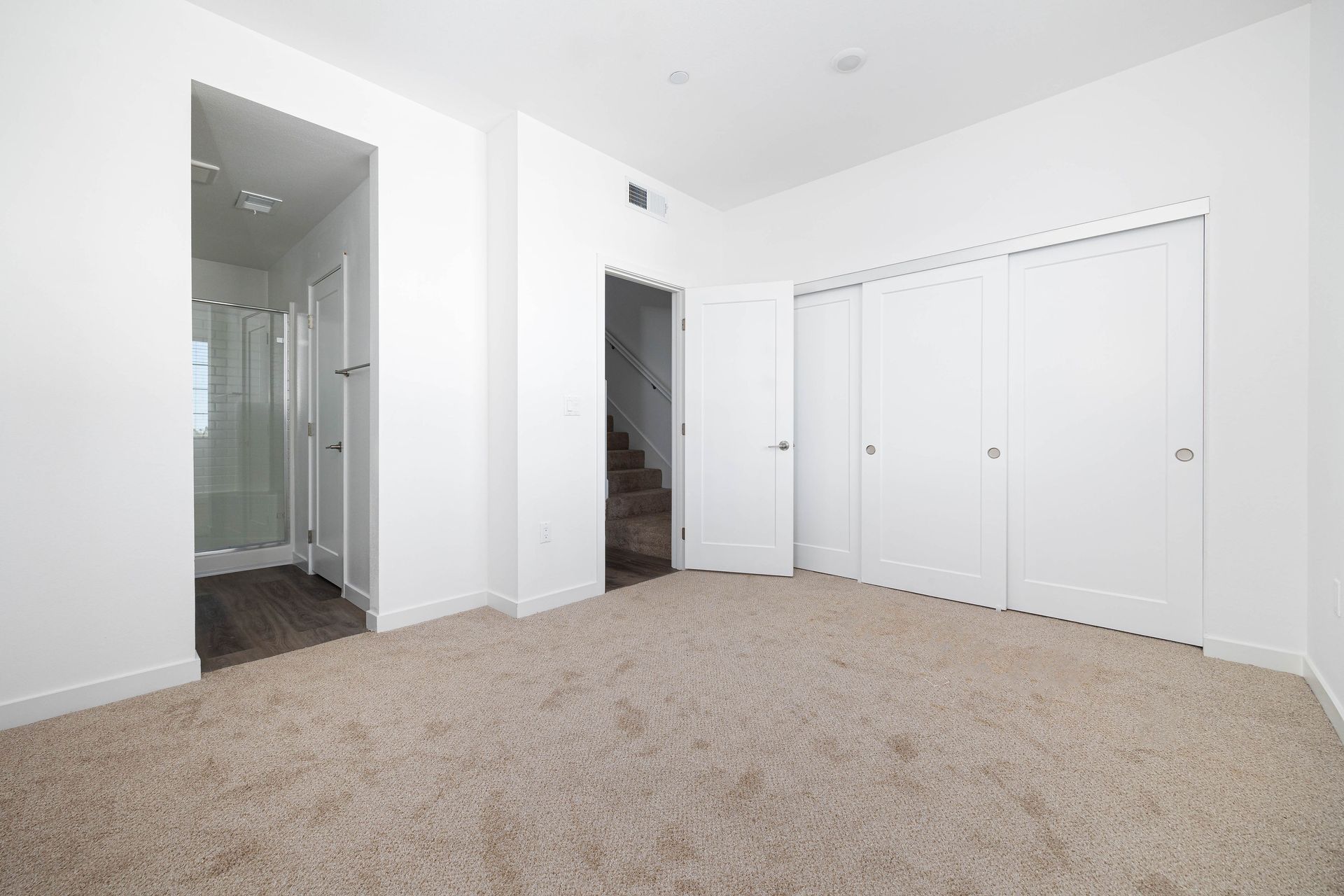 an empty bedroom with a carpeted floor and white walls .