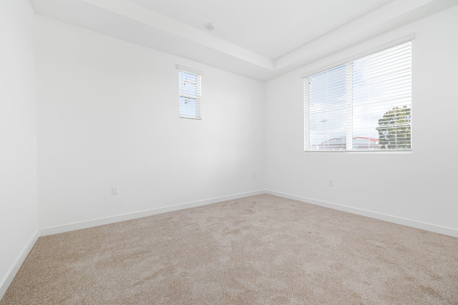 an empty bedroom with a window and carpet .