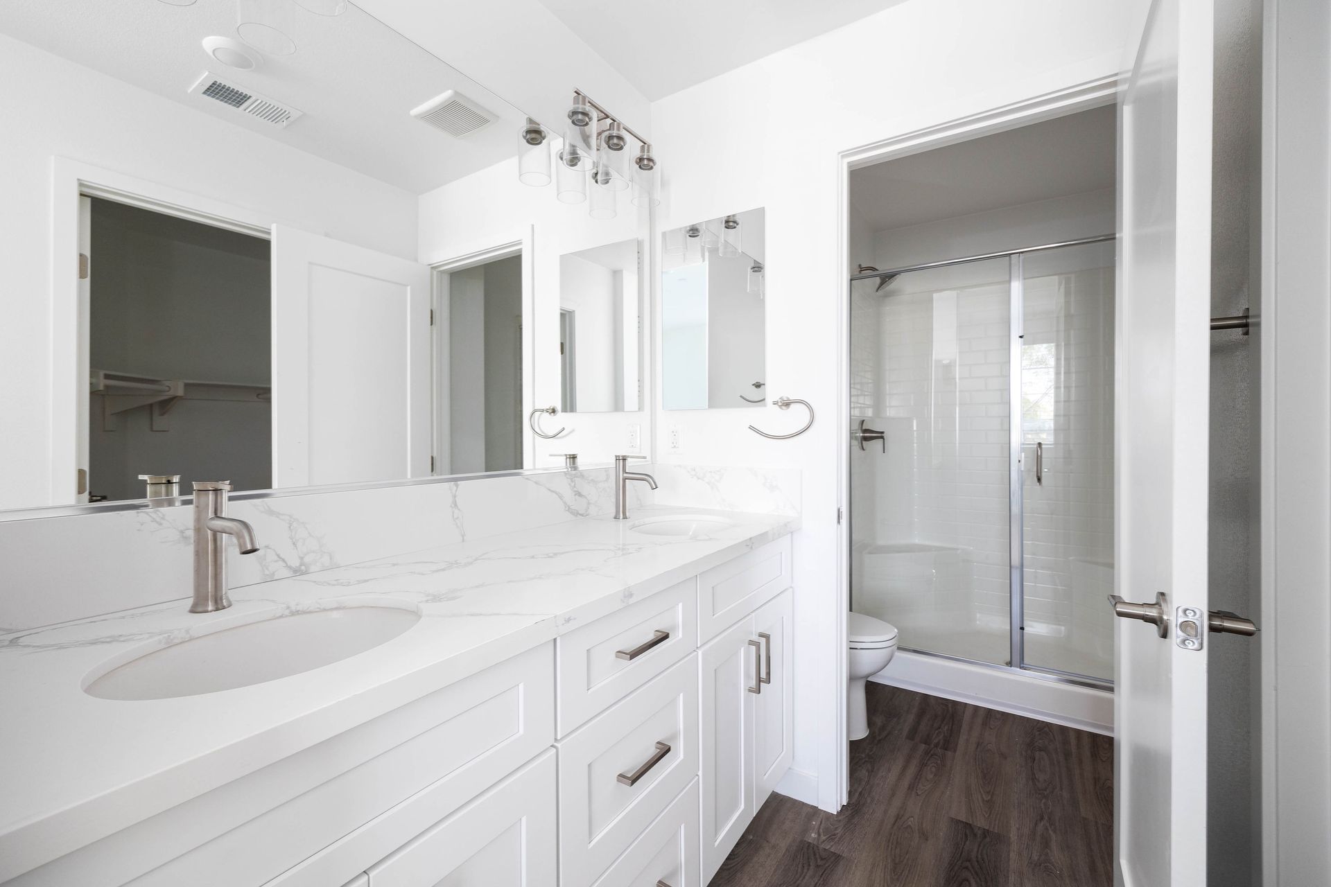 a bathroom with two sinks , a toilet , and a walk in shower .