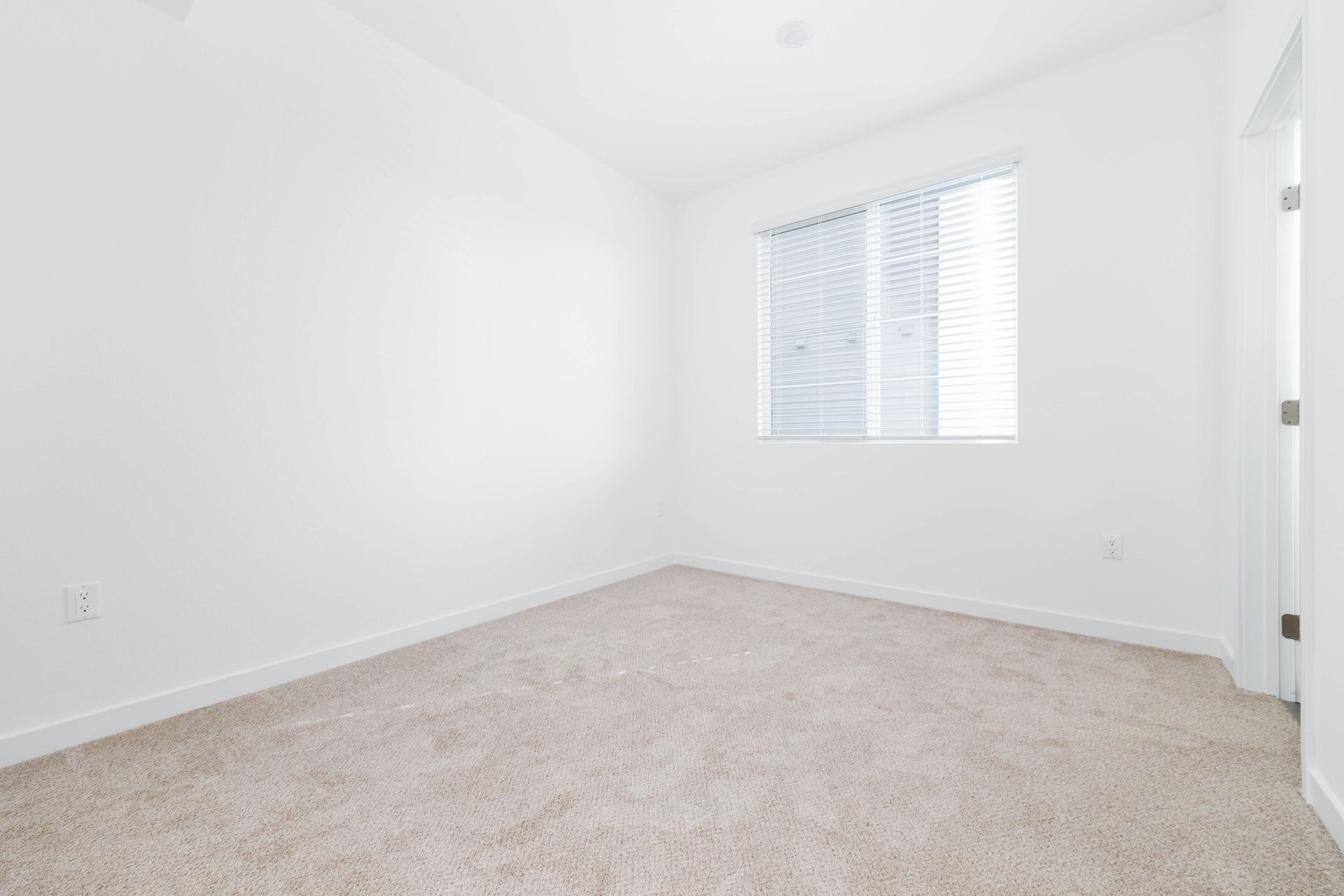 an empty bedroom with a window and carpet .