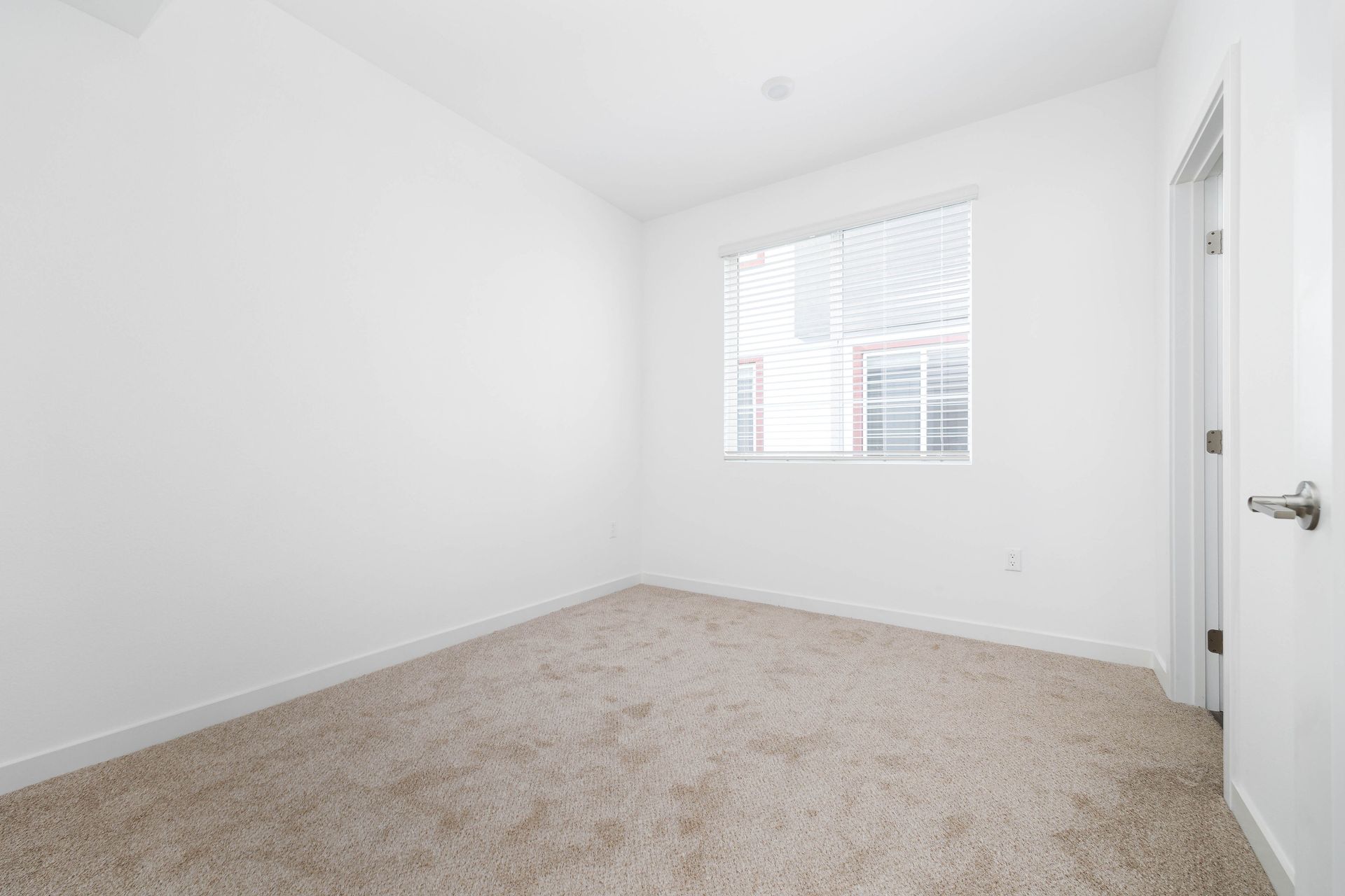 an empty bedroom with a window and carpet .
