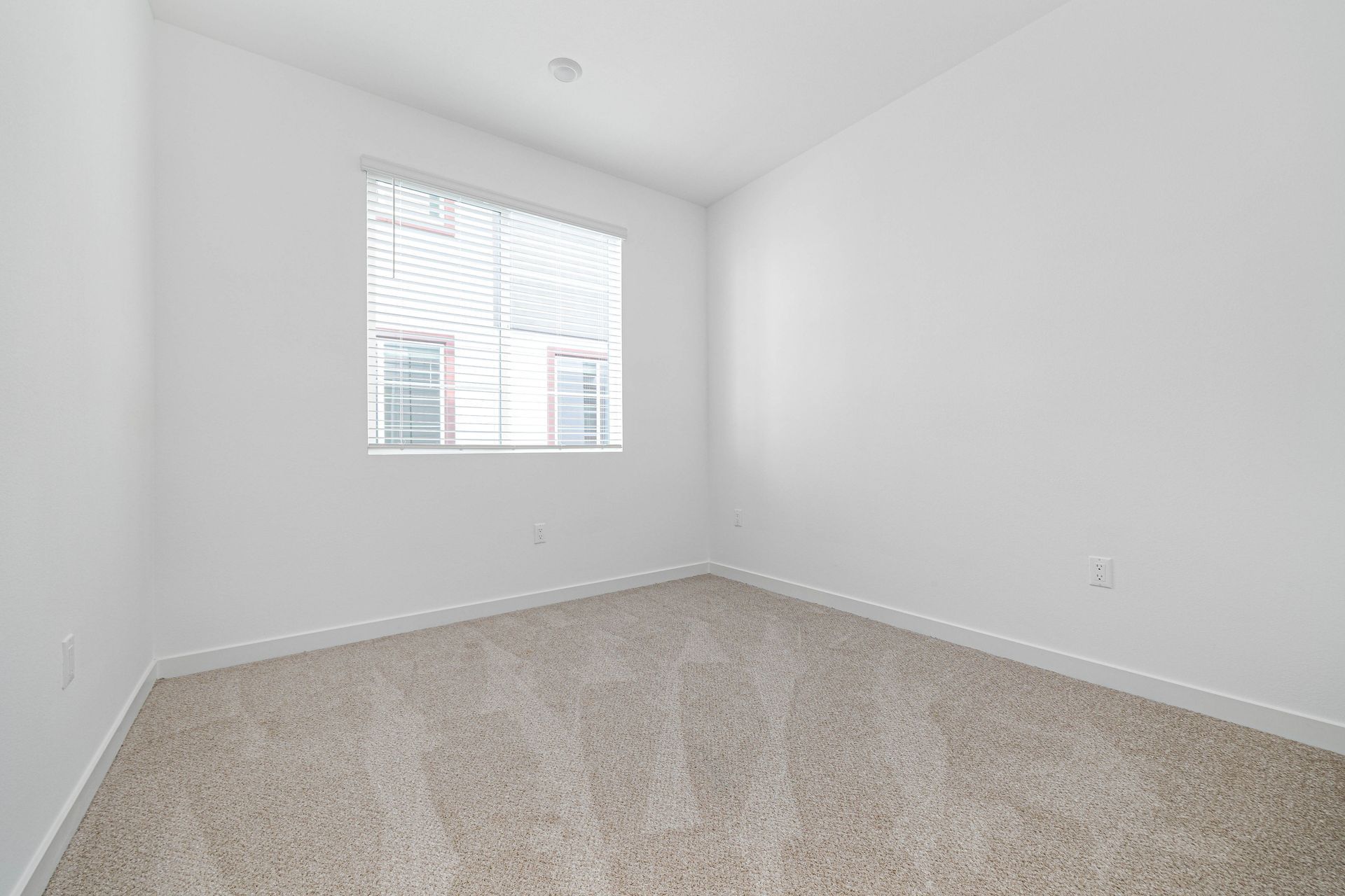 an empty bedroom with a window and carpet .