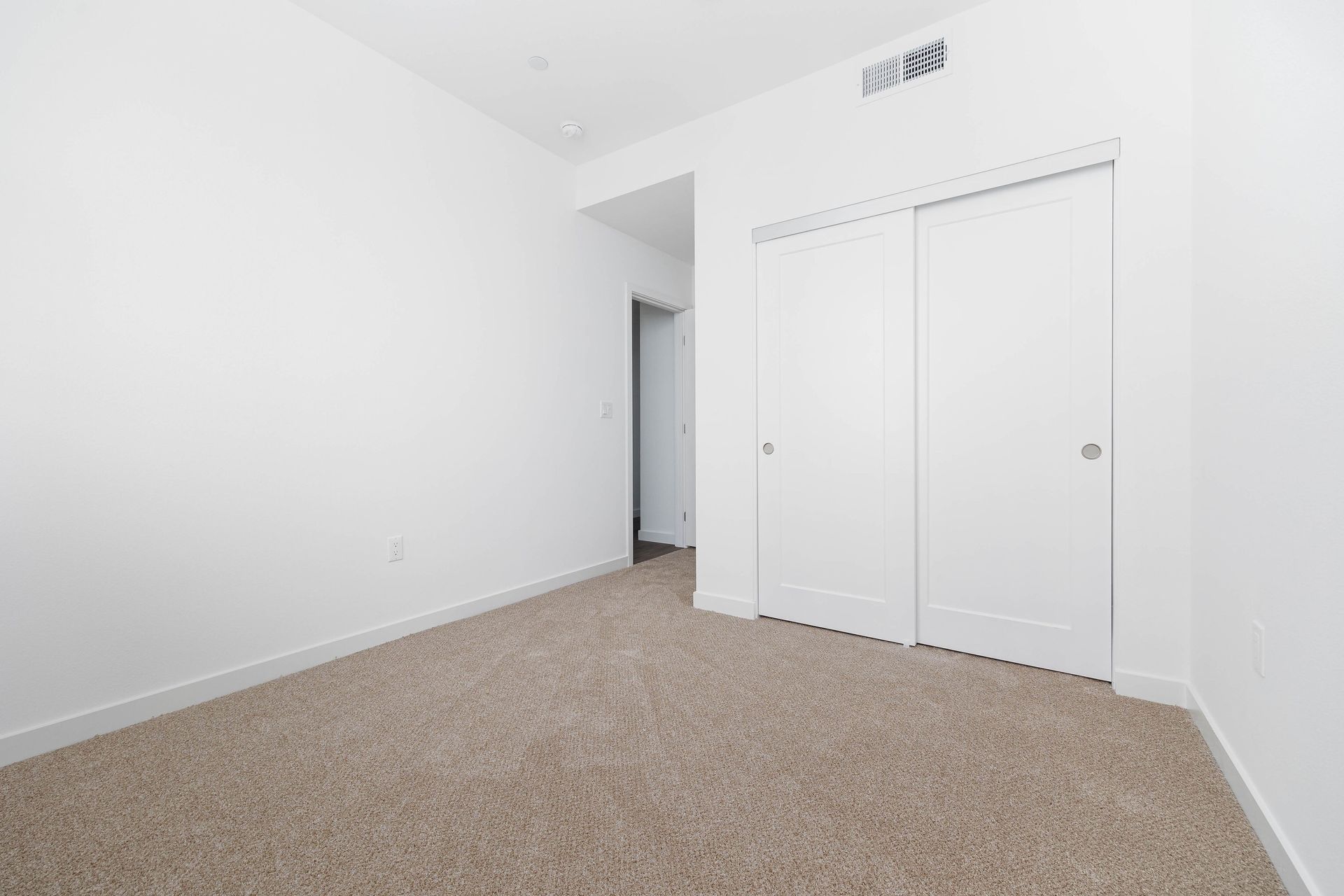 an empty bedroom with a brown carpet and white walls .
