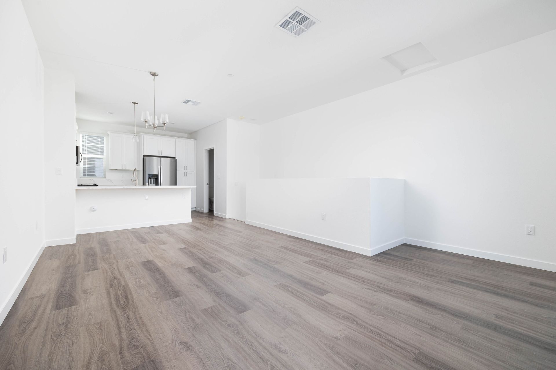 an empty living room with hardwood floors and white walls .