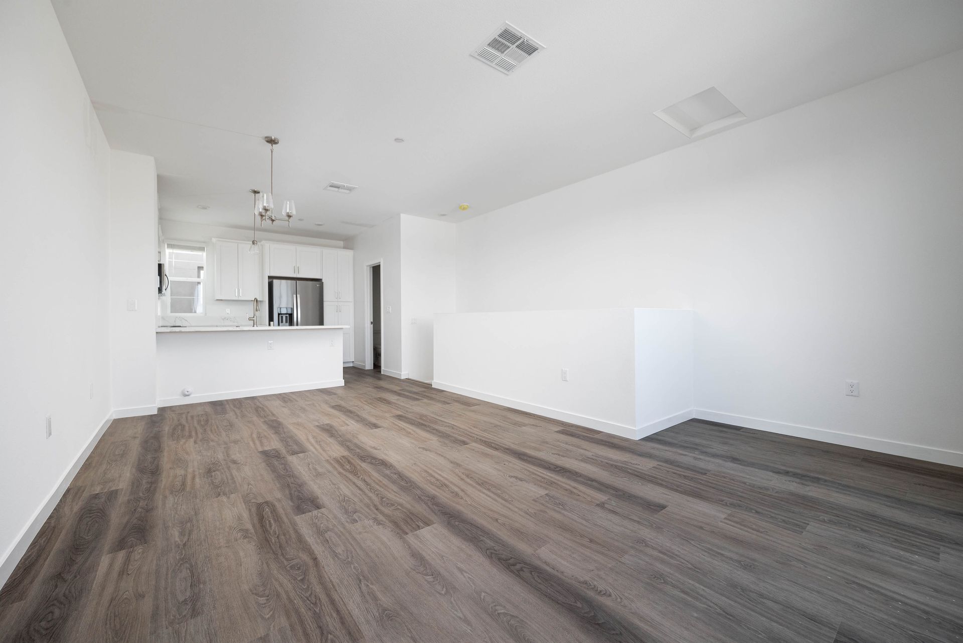 an empty living room with hardwood floors and white walls .