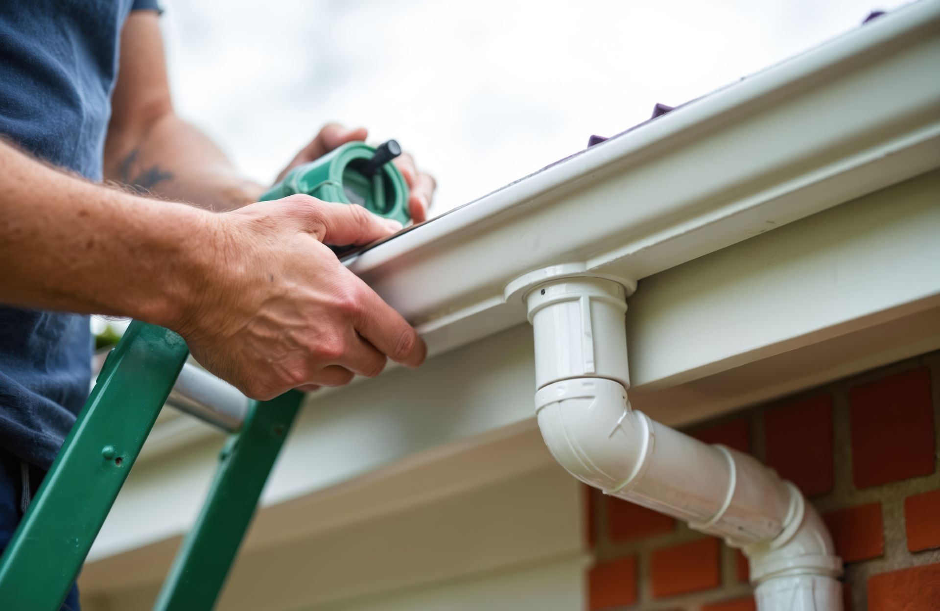 A man is measuring a gutter with a tape measure while standing on a ladder.