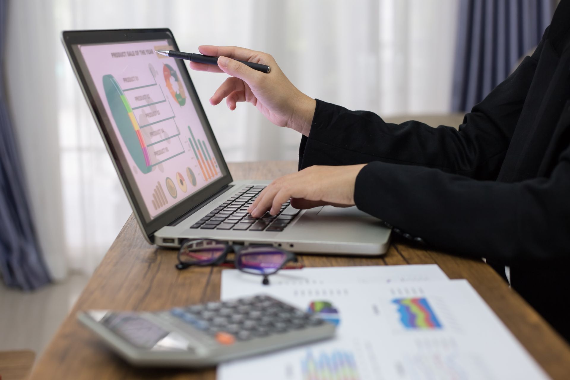 A woman is sitting at a desk using a laptop computer.