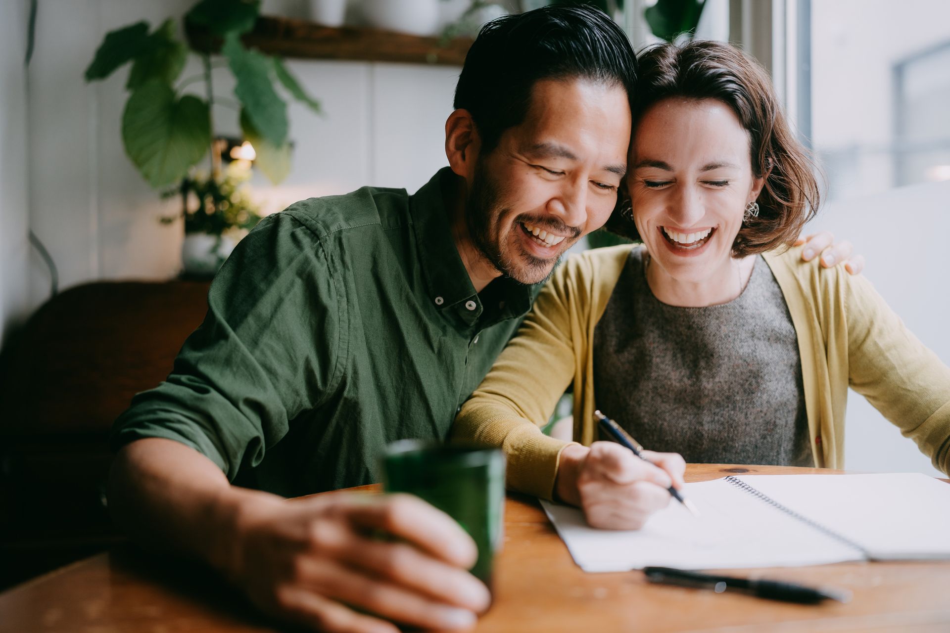 A man and a woman are sitting at a table writing on a piece of paper.
