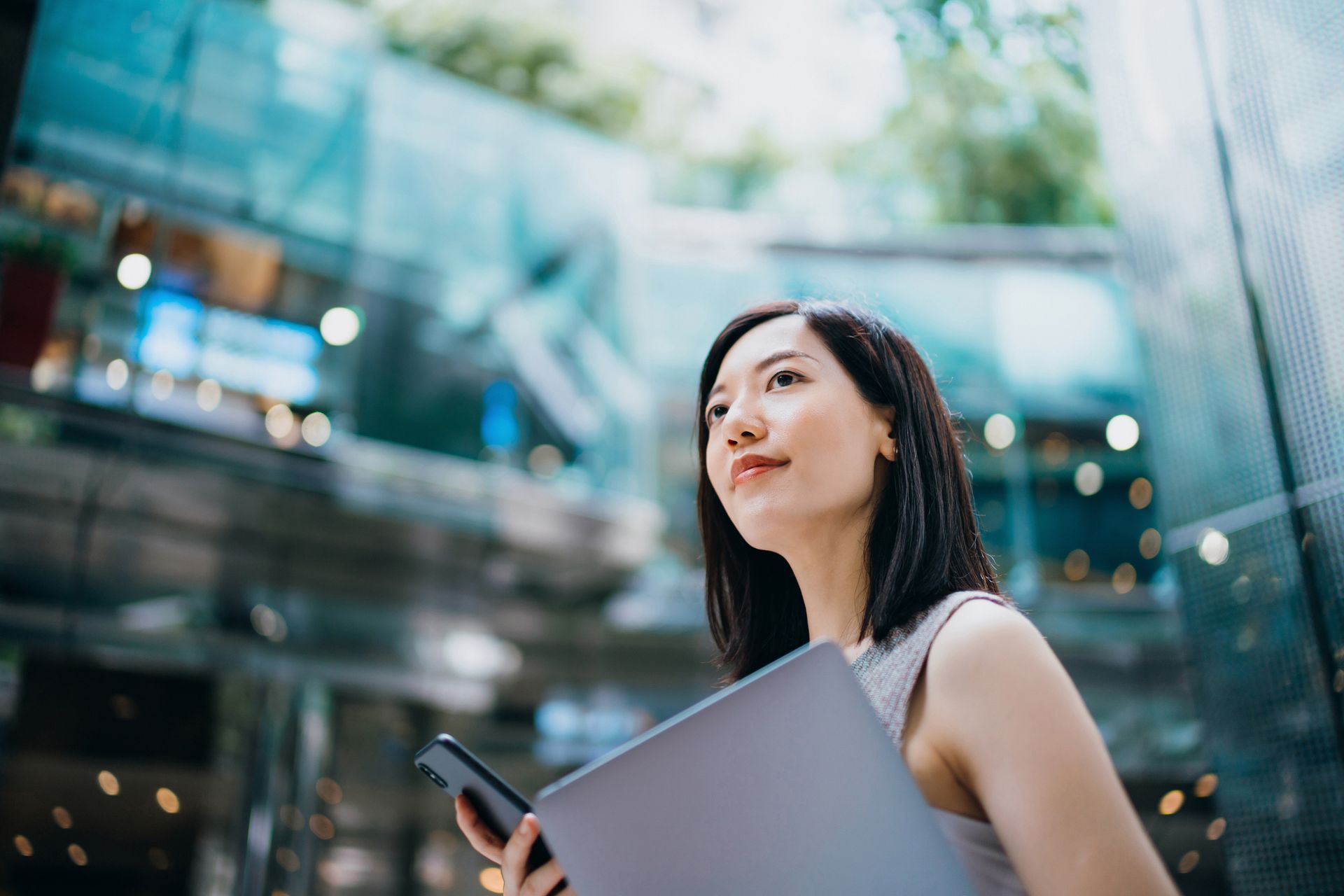 A woman is holding a laptop and a cell phone.
