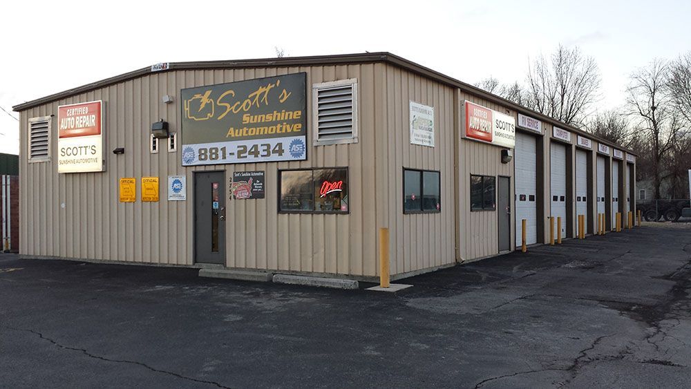 Scott's Automotive repair shop, tan building with multiple garage doors. Signs with phone number 881-2434.