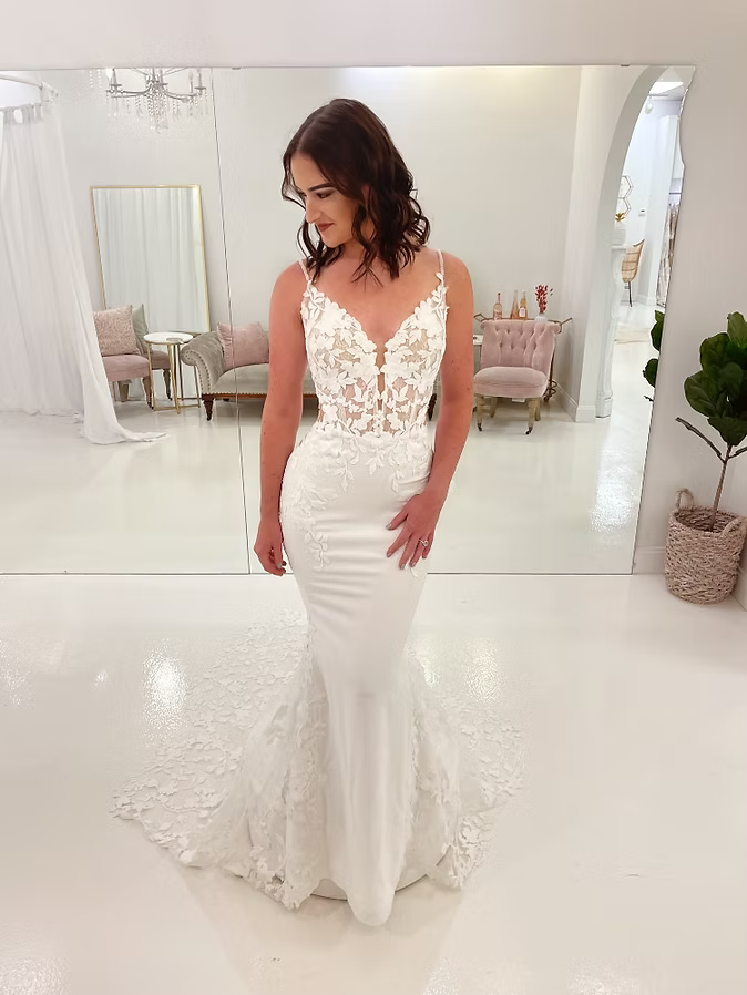 Woman in white wedding dress, lace bodice, mermaid skirt, in bridal shop.