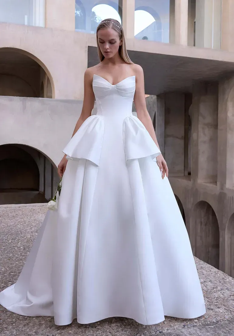 Woman in white wedding gown poses on stone steps outdoors.