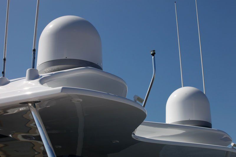 Two white antennas on top of a boat against a blue sky