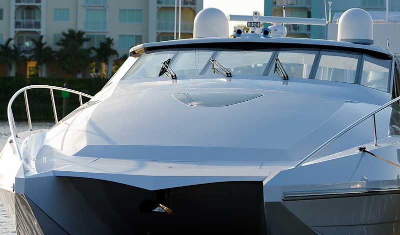 A large white boat is docked in a harbor with buildings in the background.