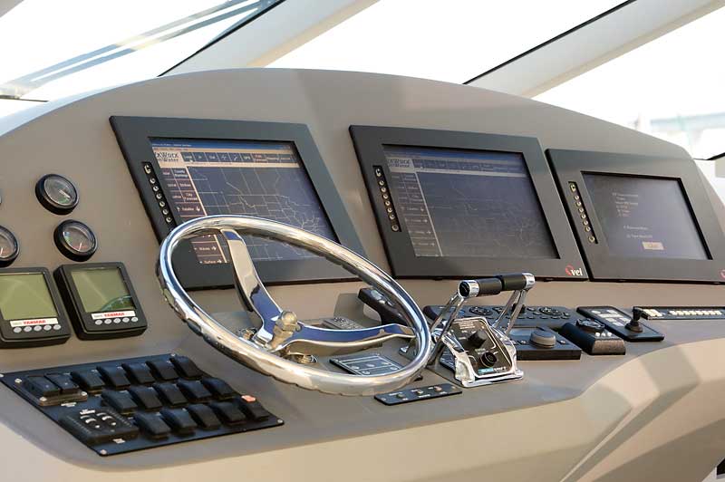 A steering wheel and dashboard of a boat with monitors