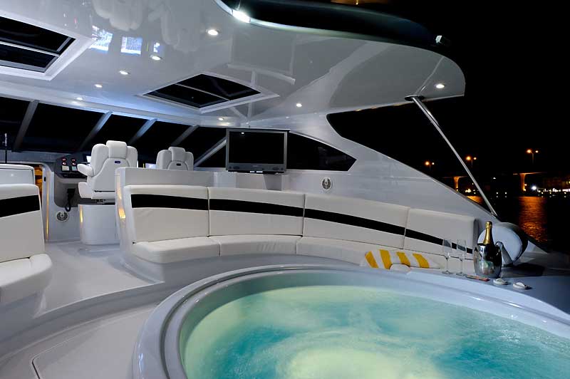 A boat with a jacuzzi on the deck at night