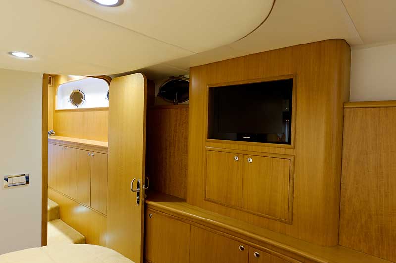 A bedroom with a bed and a television on the wall.