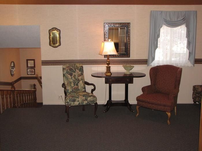 A living room with two chairs a table and a lamp