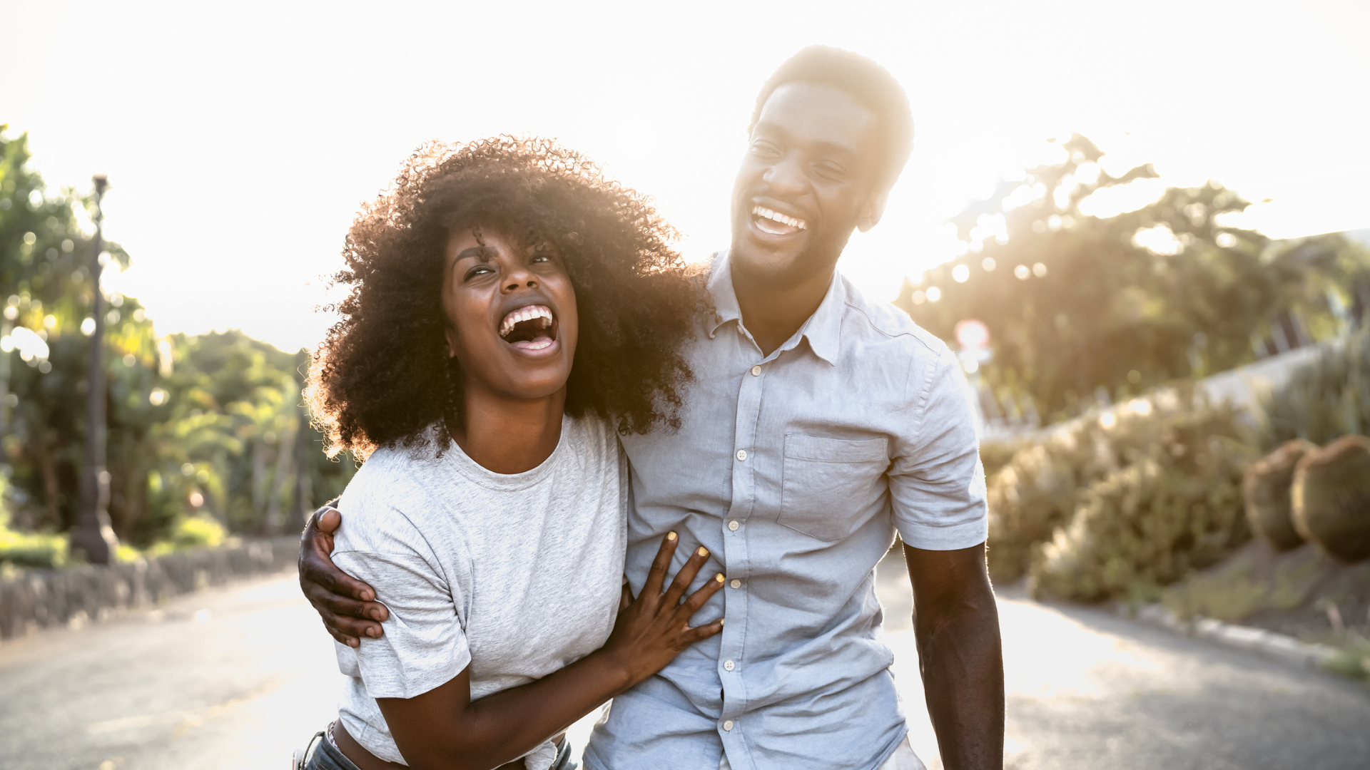 A man and a woman are laughing together while walking down a street.