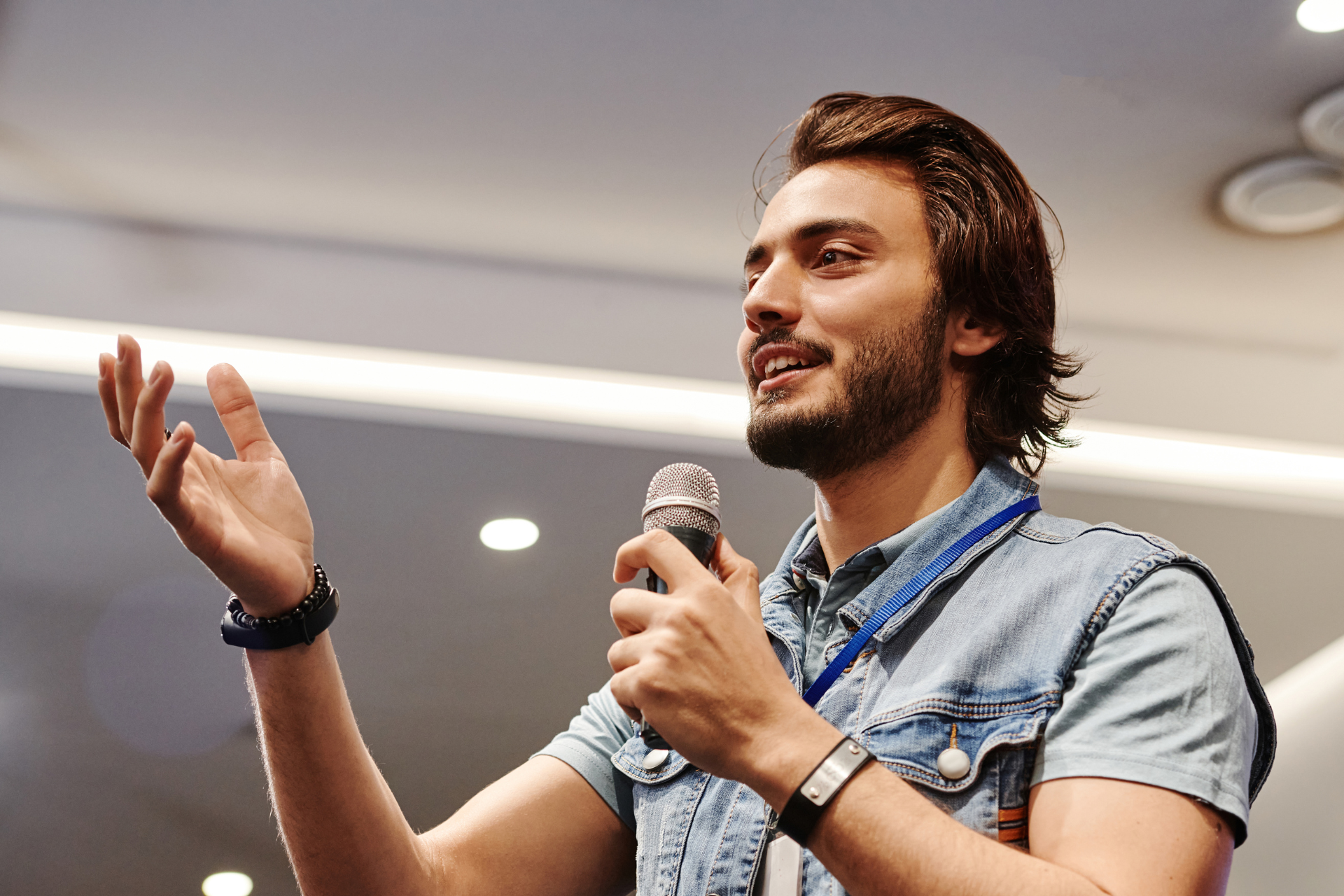 A man with a beard is holding a microphone and giving a speech.