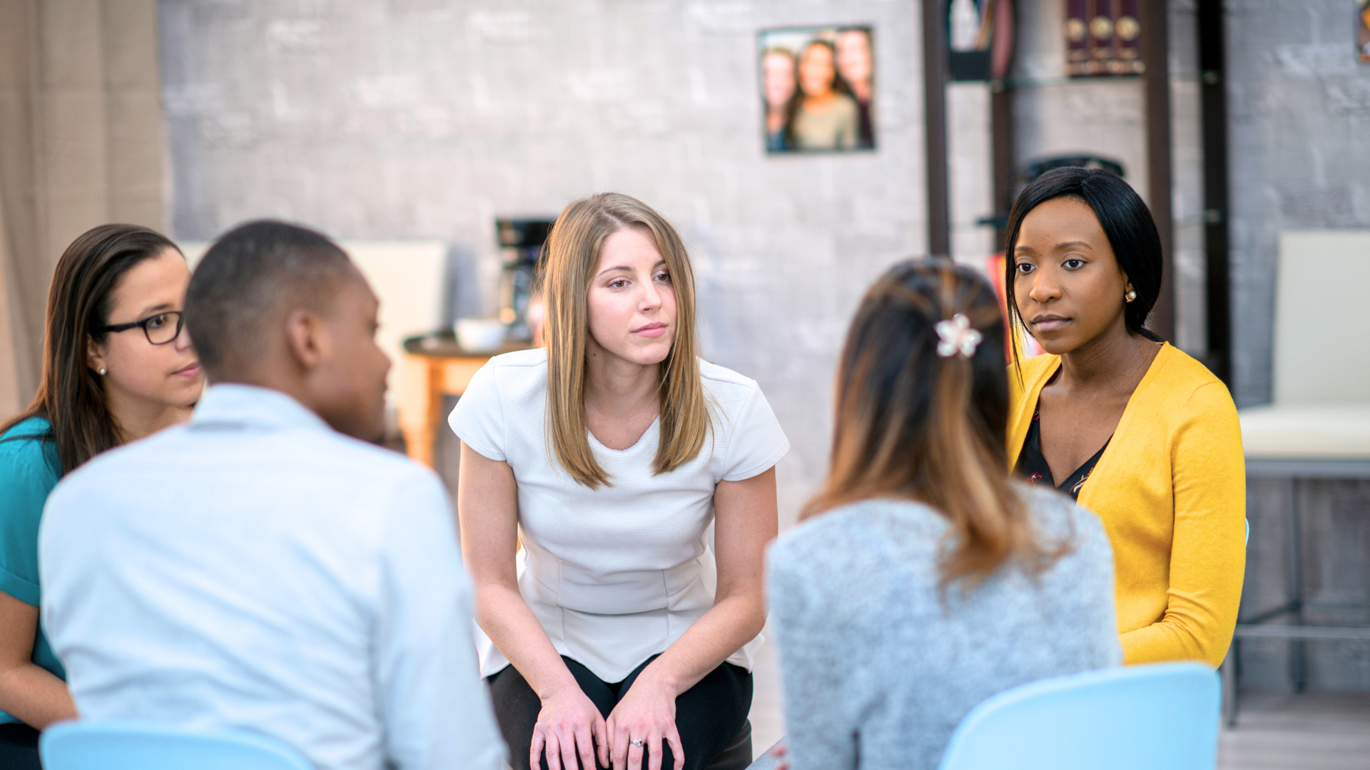 A group of people are sitting in a circle talking to each other.