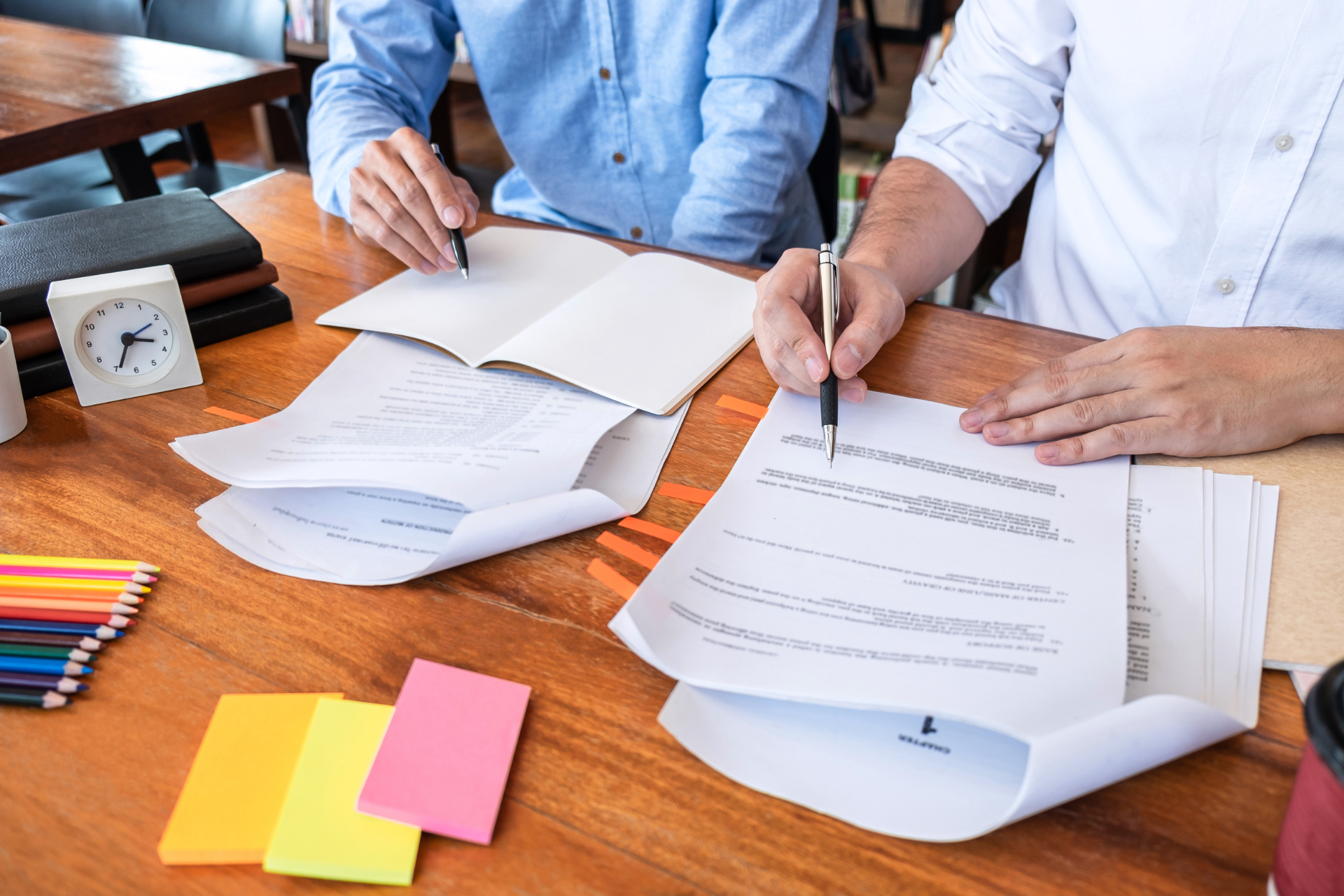 Two people are sitting at a table writing on papers.