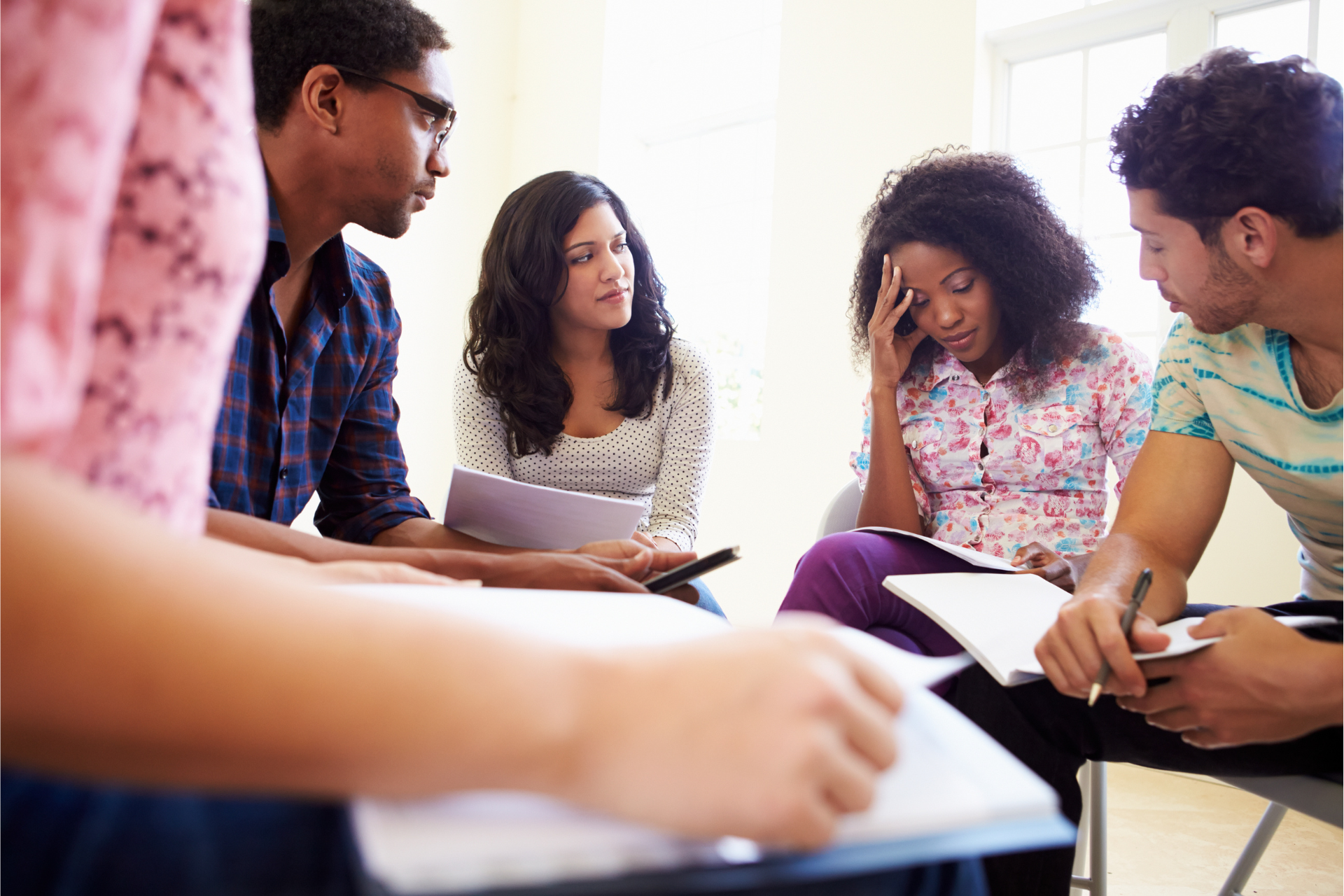 A group of young people are sitting around a table talking to each other.