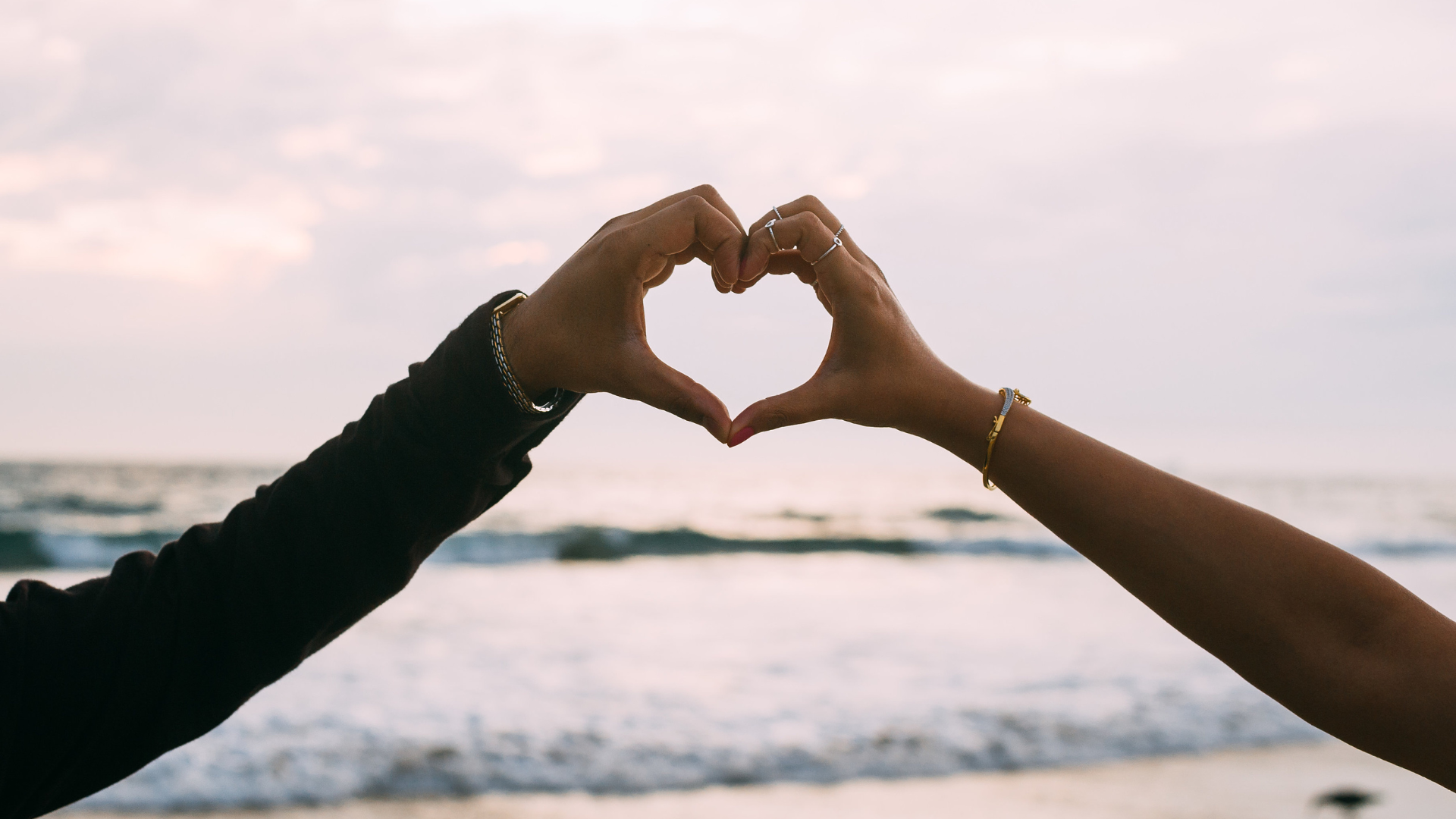 A man and a woman are making a heart shape with their hands.