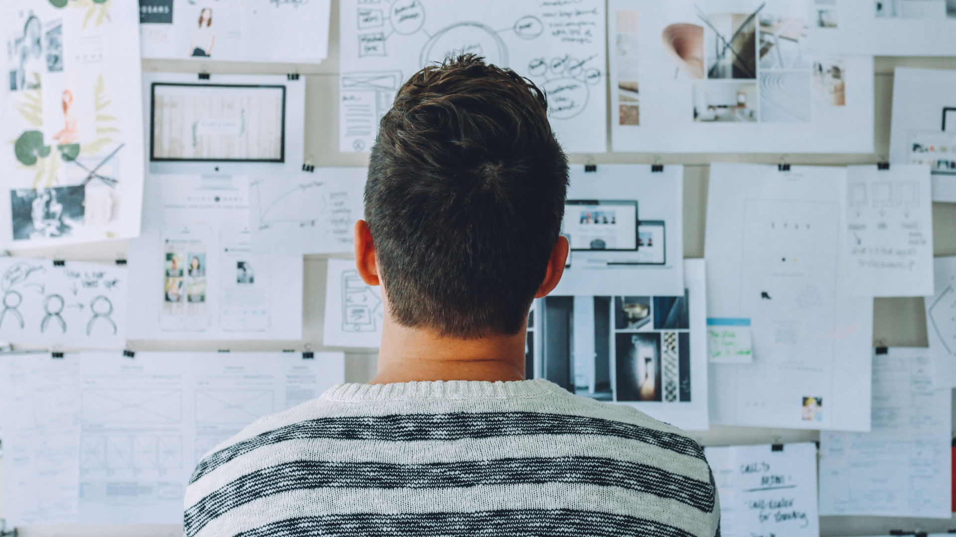 A man is looking at a wall full of papers.