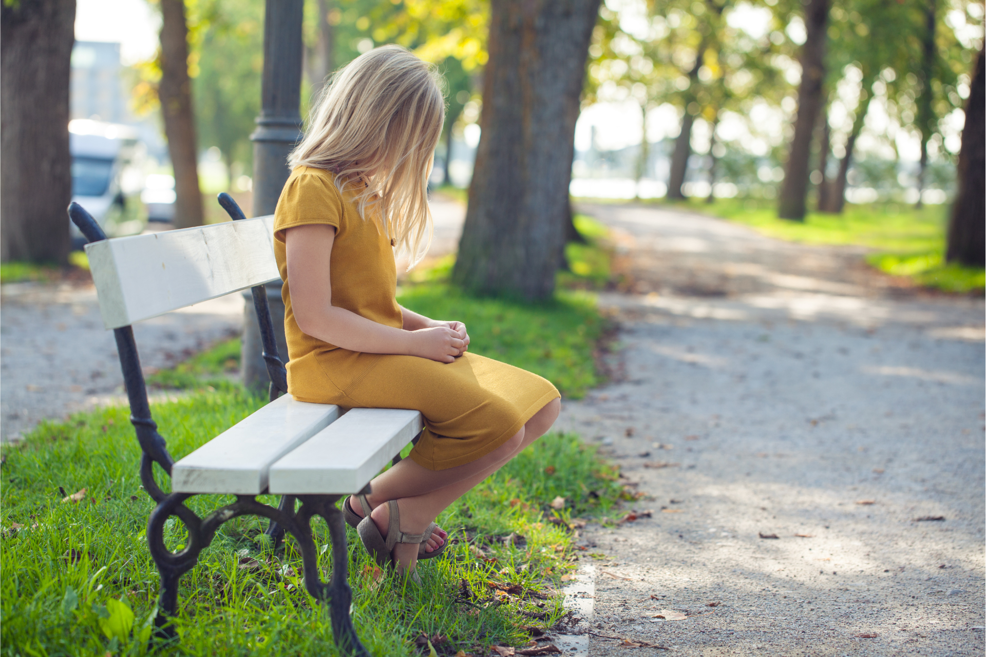 A young girl is sitting on a park bench.