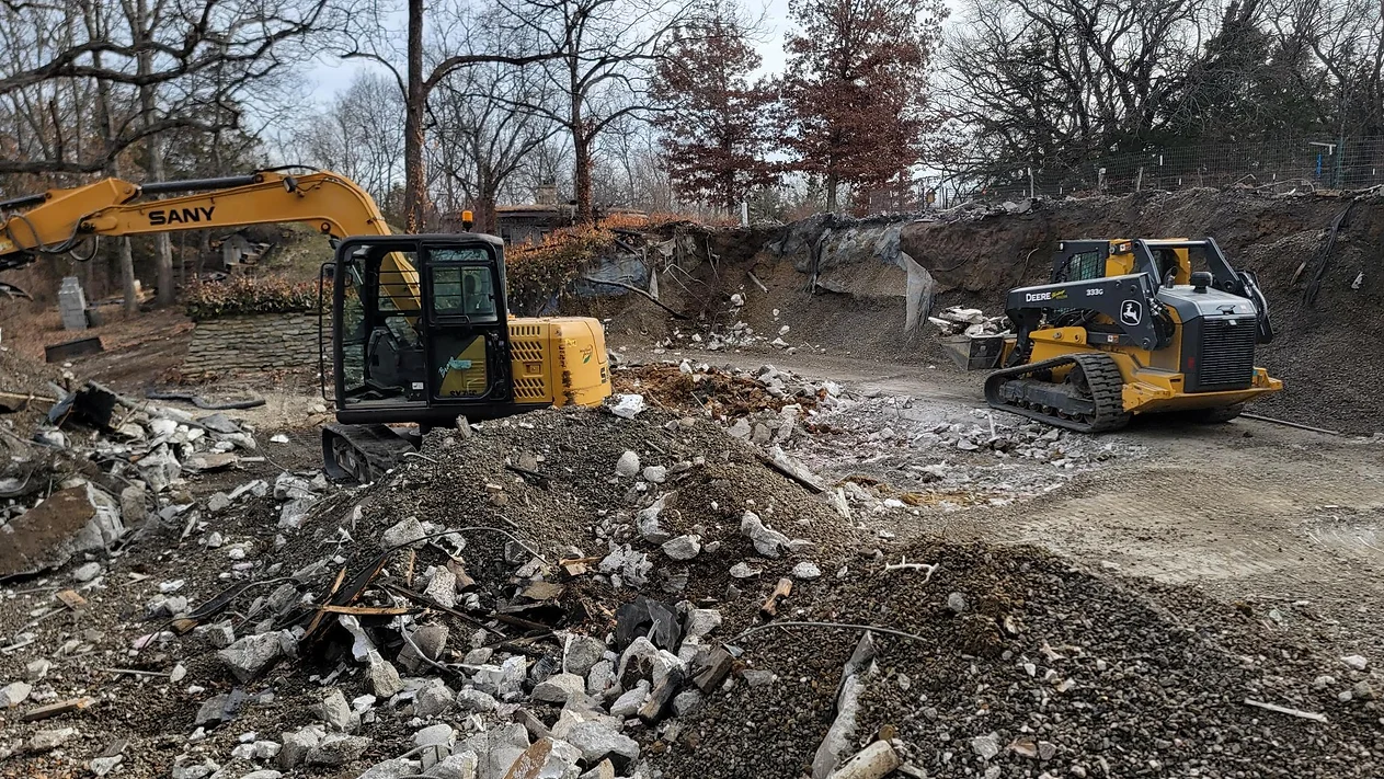 A couple of construction vehicles are driving through a pile of dirt.