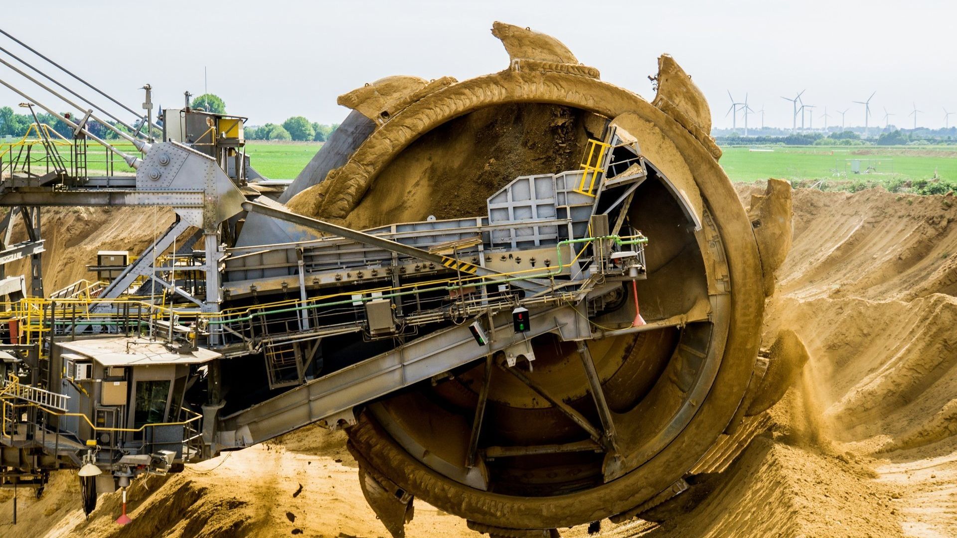 A large wheel excavator is digging a hole in a dirt field.