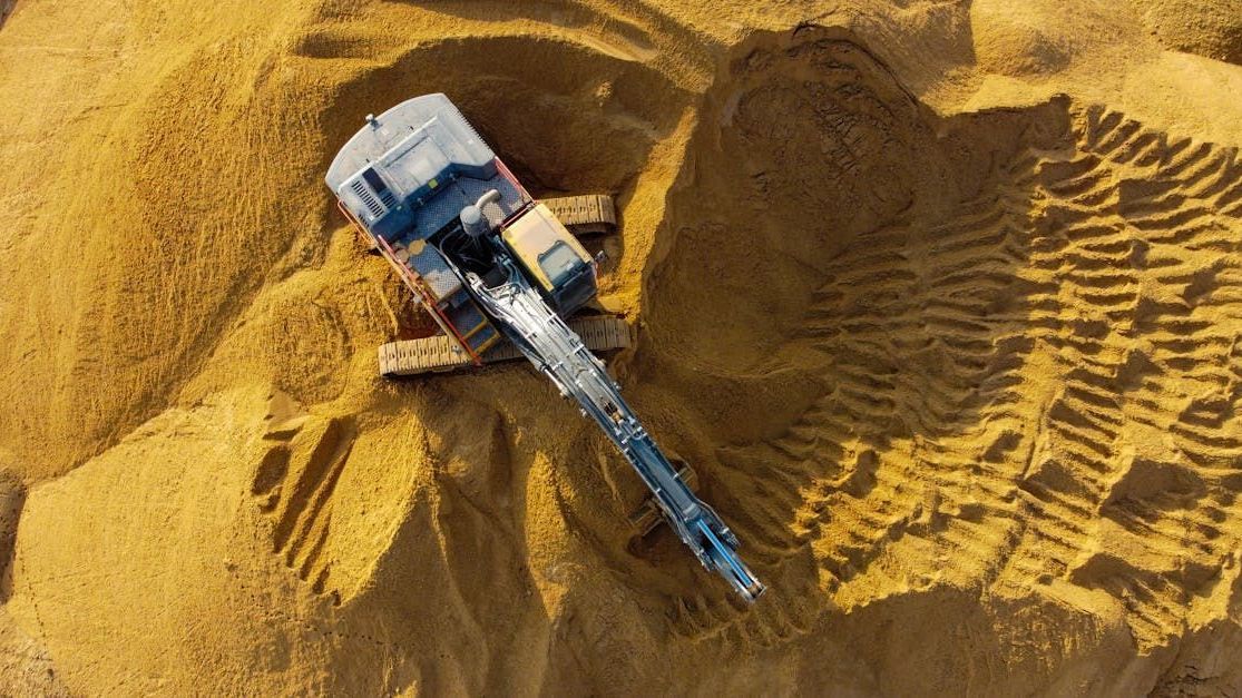 An aerial view of a bulldozer working on a pile of sand.