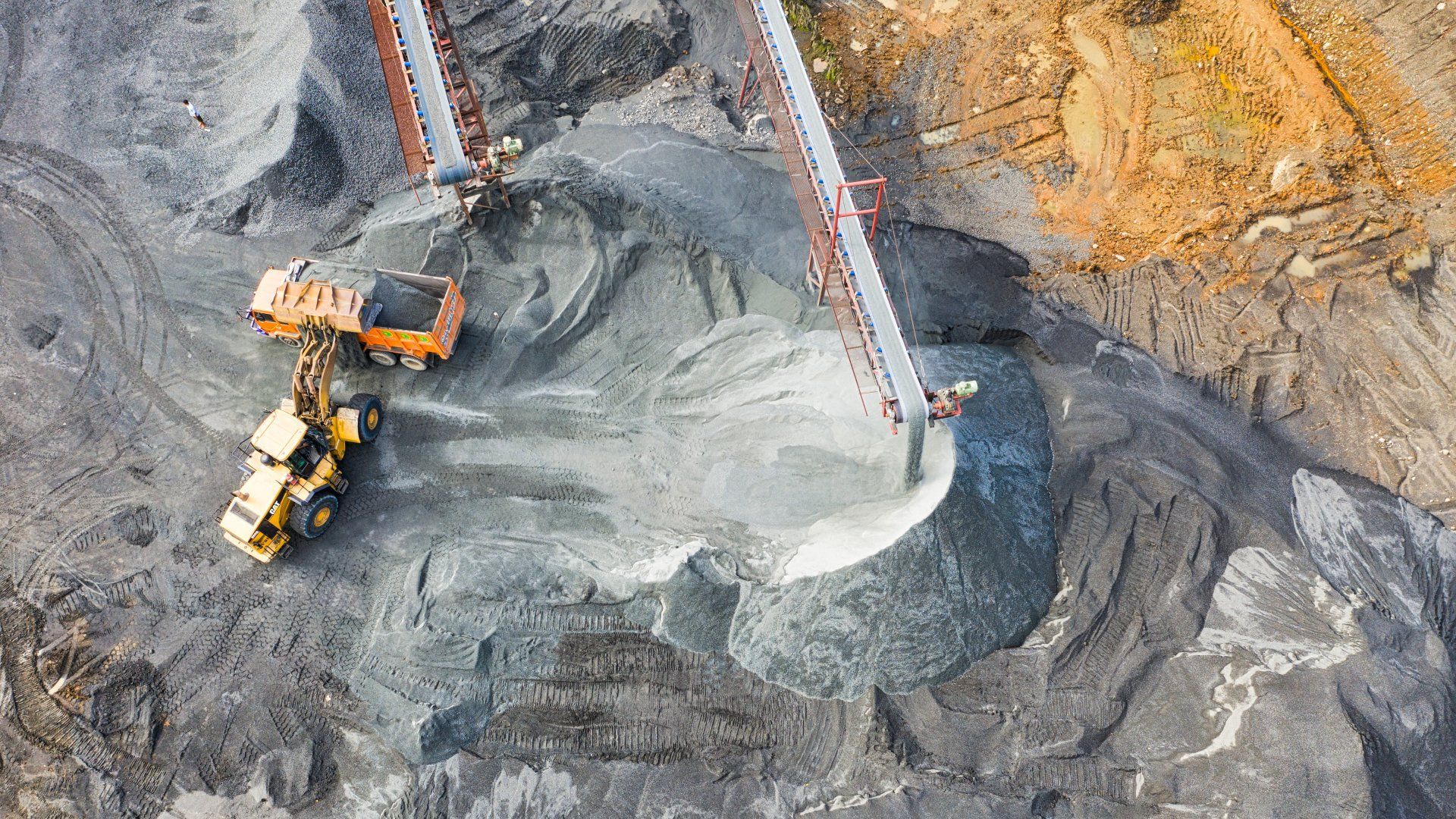 An aerial view of a coal mine with a bulldozer and a conveyor belt.