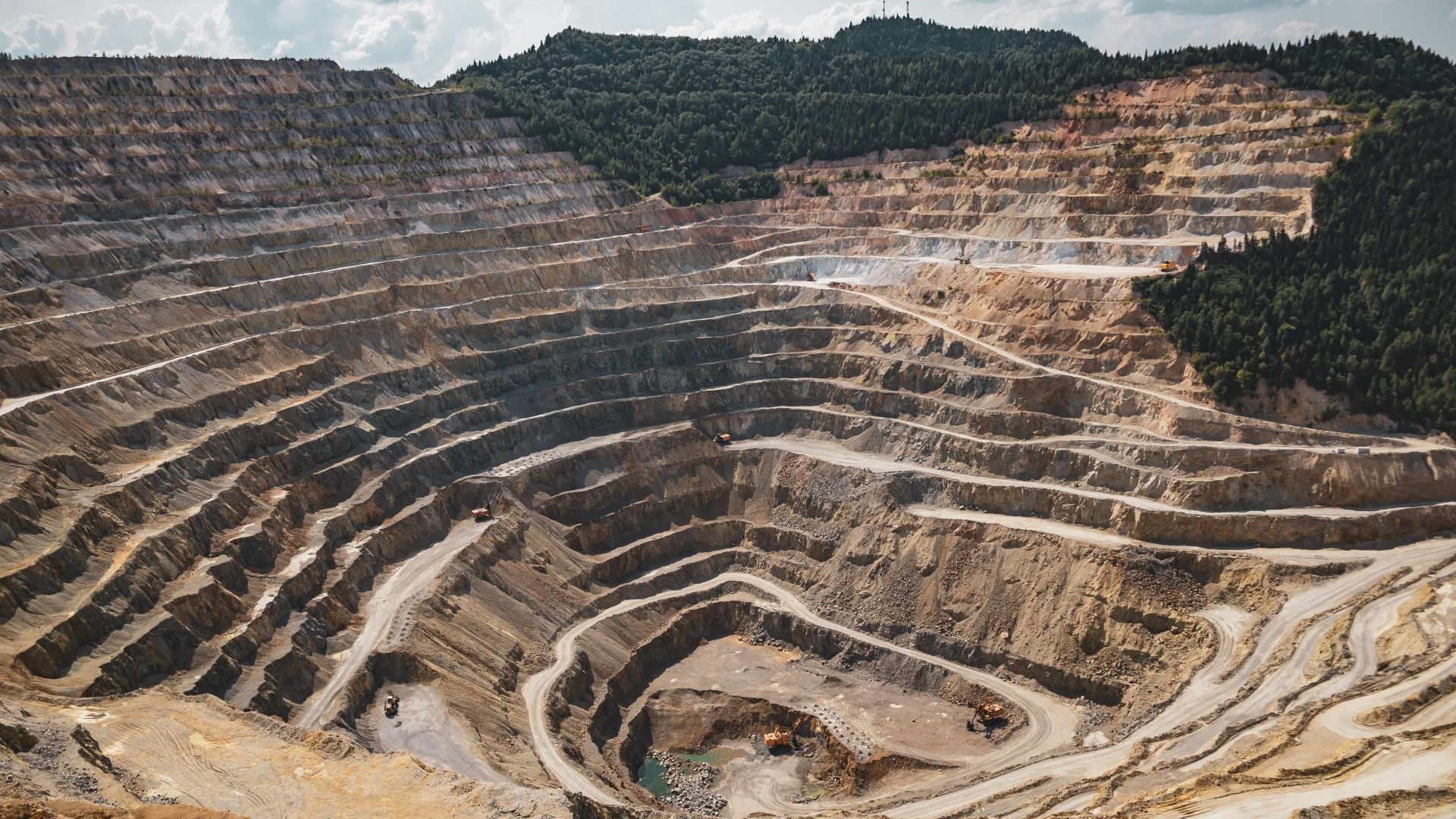 An aerial view of a large open pit mine surrounded by trees.