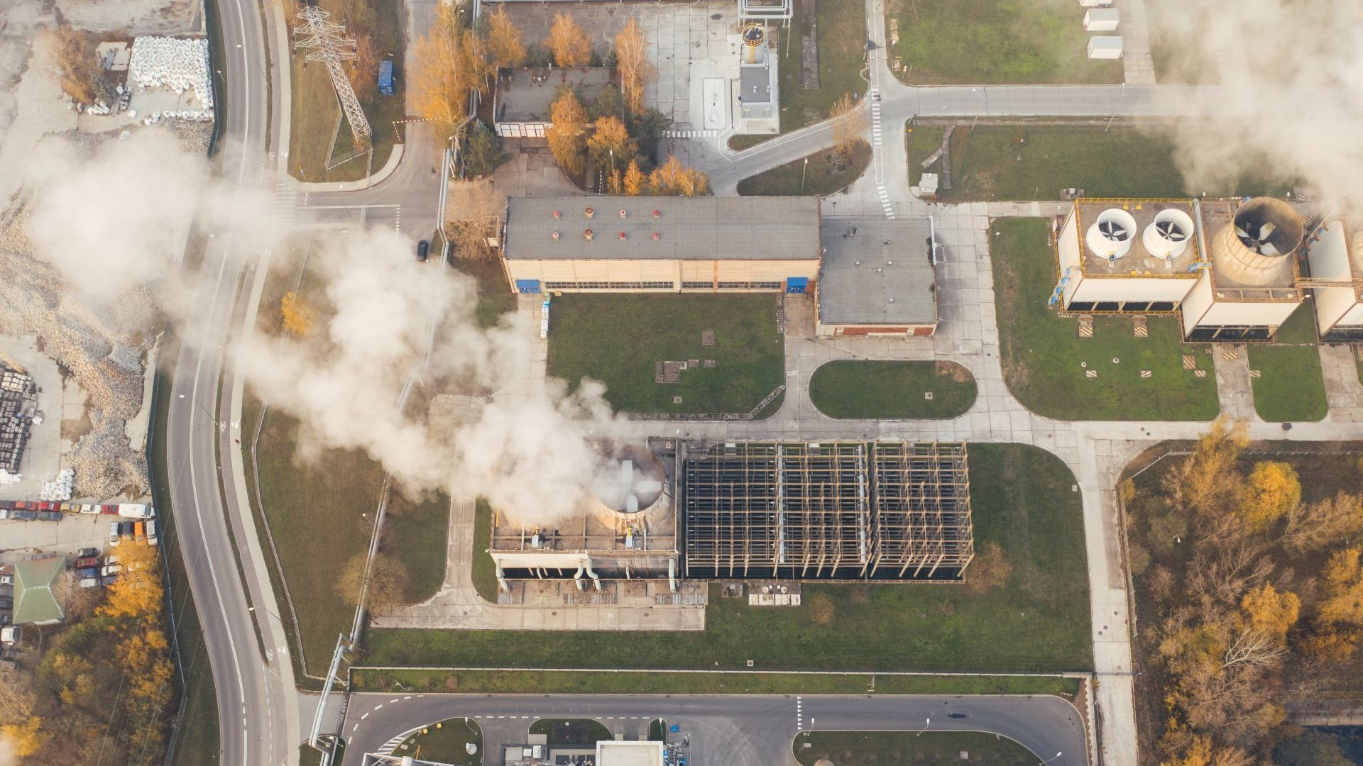 An aerial view of a factory with smoke coming out of the chimneys.