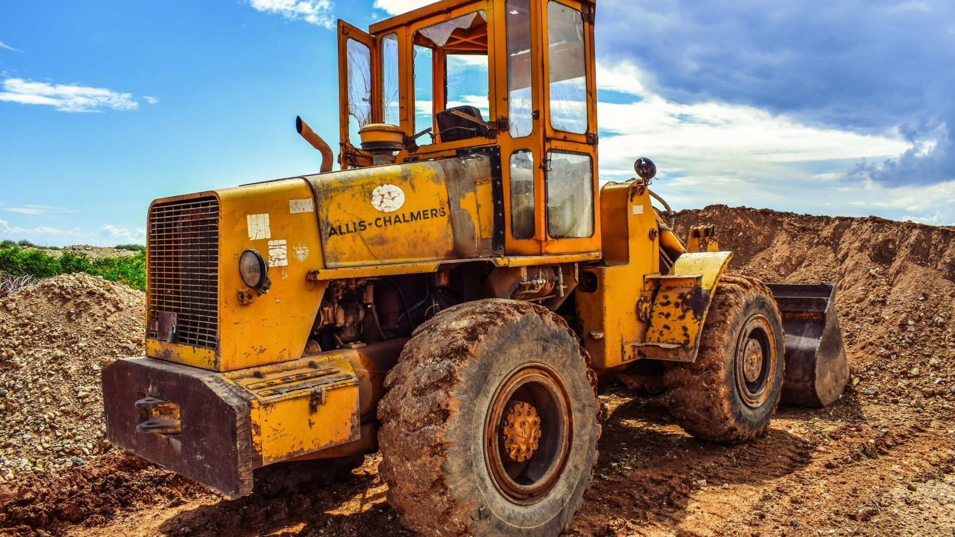 A yellow bulldozer is parked in a dirt field.