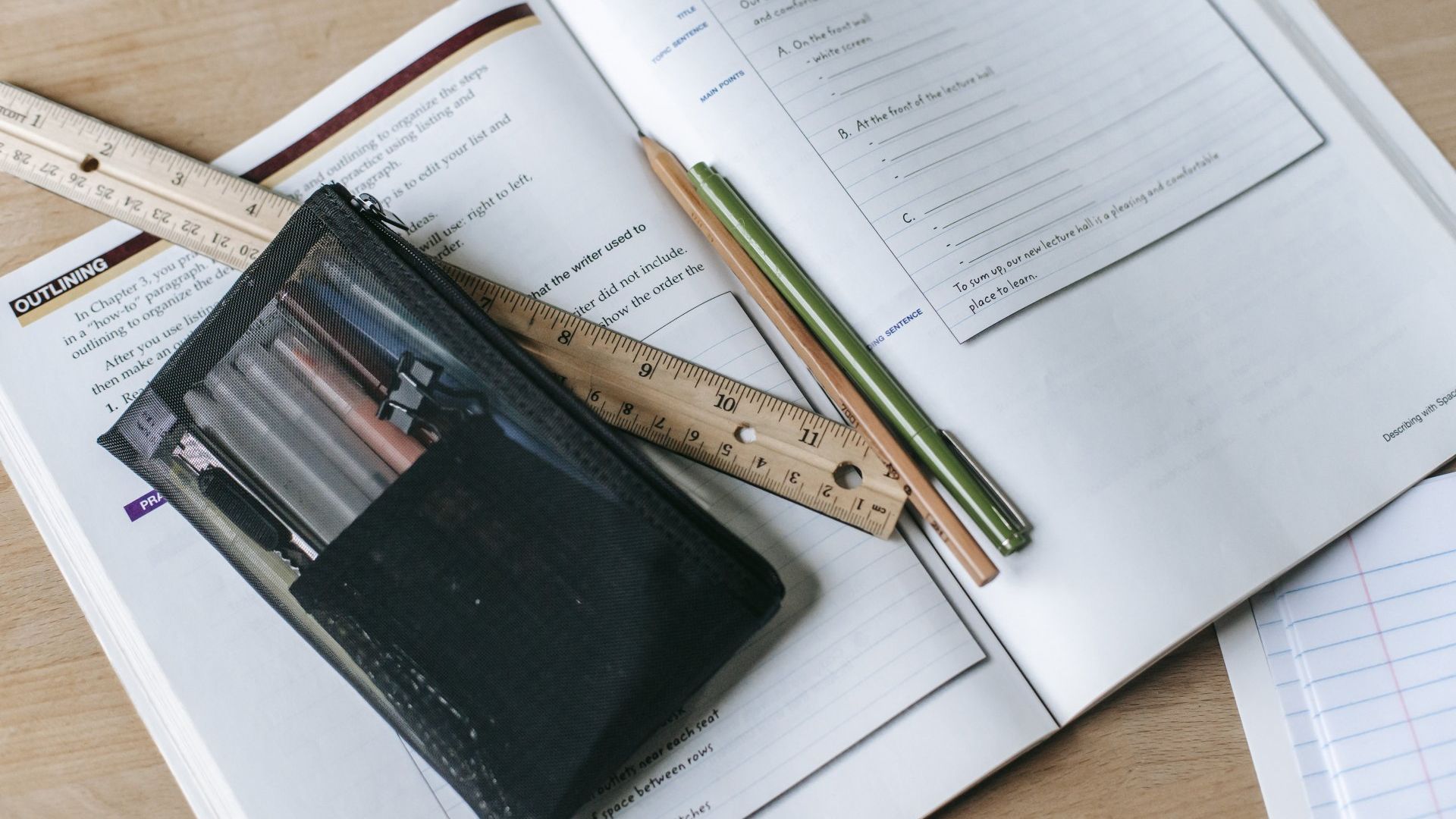 A ruler and pencils are sitting on top of a notebook.