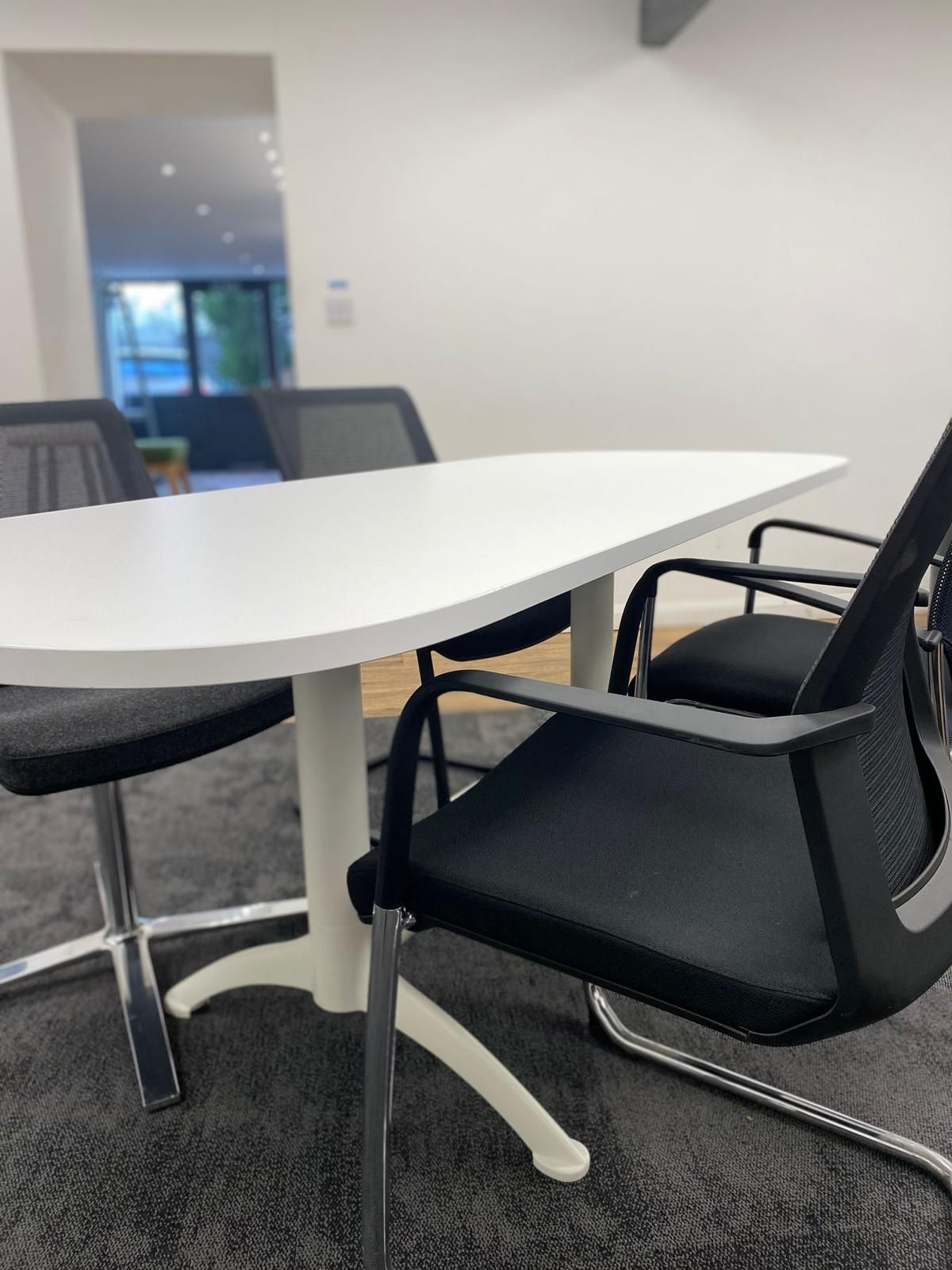 White table with black chairs in a modern office setting.