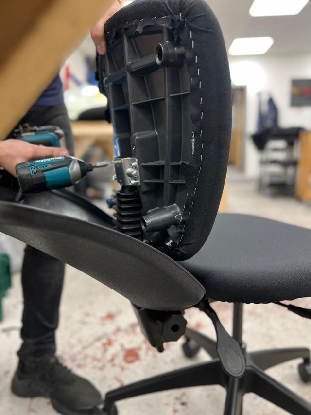 A chair back being refitted with a power drill
